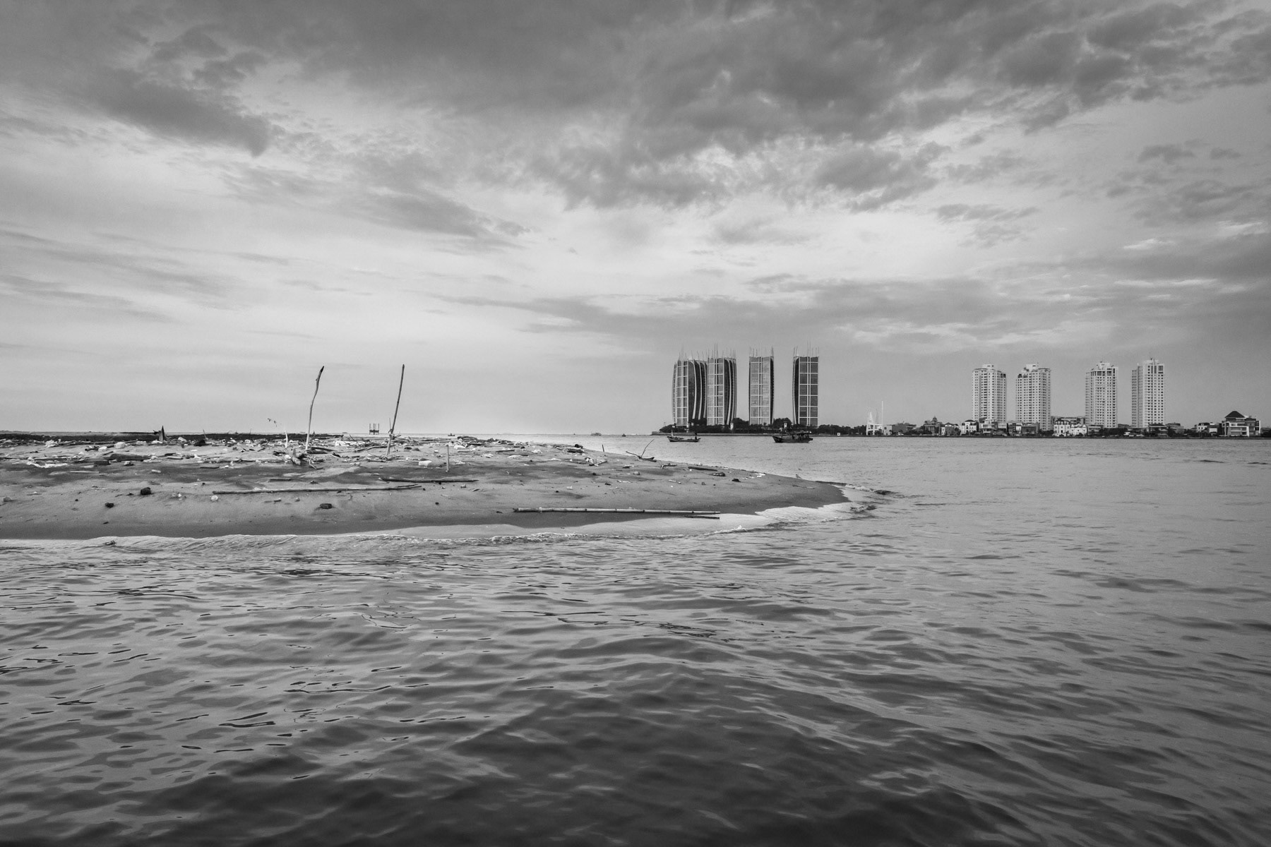 Artificial island in the Bay of Jakarta to be further developped as an exclusife real estate secluded cluster as the one in the background. Such real estate development projects have a very nefast environmental and social impact, such as blocking natural river outflow, depleting drinking water reserves provoking soil sinking, changing sea currents affecting fish reserves, and evictions. Muara Angke, Bay of Jakarta, Indonesia, March 2020