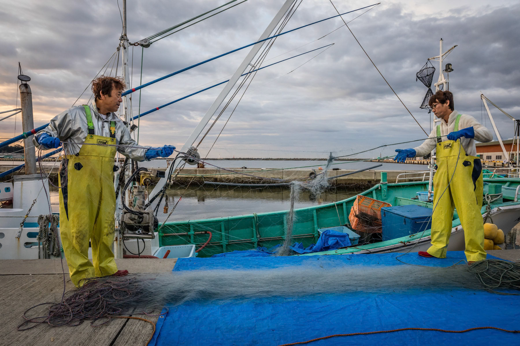 A fishermen sorting their nets. The fishing community has been gravely affected by the Tsunami and many died trying to save their boats. The surviving fishermen have been banned from fishing for many years after the nuclear catastrophy. Only in the past couple of years has fishing being allowed again under very stringent radiation controls. Onamaha fishing port, Fukushima Prefecture, Japan, October 2019