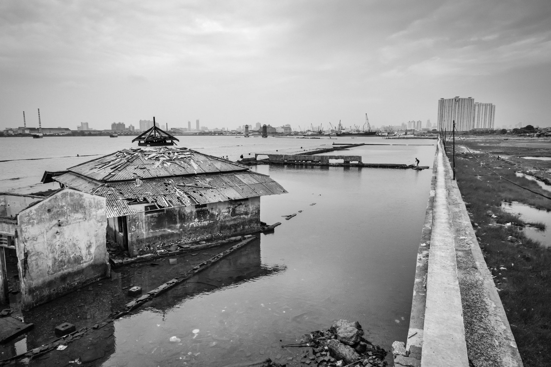 An abandonned mosque on the wrong side of the eawall built against floods provoked by rising sea levels and sinking soil. The soil is sinking at a rate of 10 to 20cm per year. The unstability of the ground is provoked by widespread drilling of water wells for new real estate projects, creating huge air pockets once the water is exhausted. Most of the lands in North Jakarta lay up to 2 metres under sea level accelerating land loss and evictions of indigenous communities, North Jakarta, Indonesia, March 2020