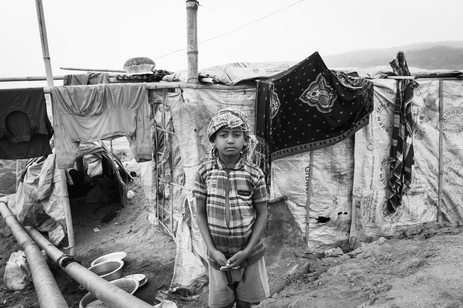 Child worker in front of his family makeshift shelter at the stone extraction site of Jaflong, Bangladesh, December 2015