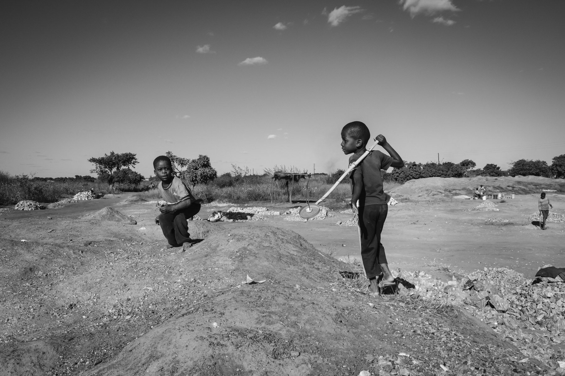 Boys playing near an open pit mine where lead is being mined. The soil in and around the city of Kabwe contains life-threatening levels of soil particles containing lead. The amount is estimated to be 10 times above WHO safety limits and even much higher in hotspots. Children are particulary vulnerable as they have the tendency to swallow the most when playing outside in a dusty environment. Kabwe, Zambia, May 2021