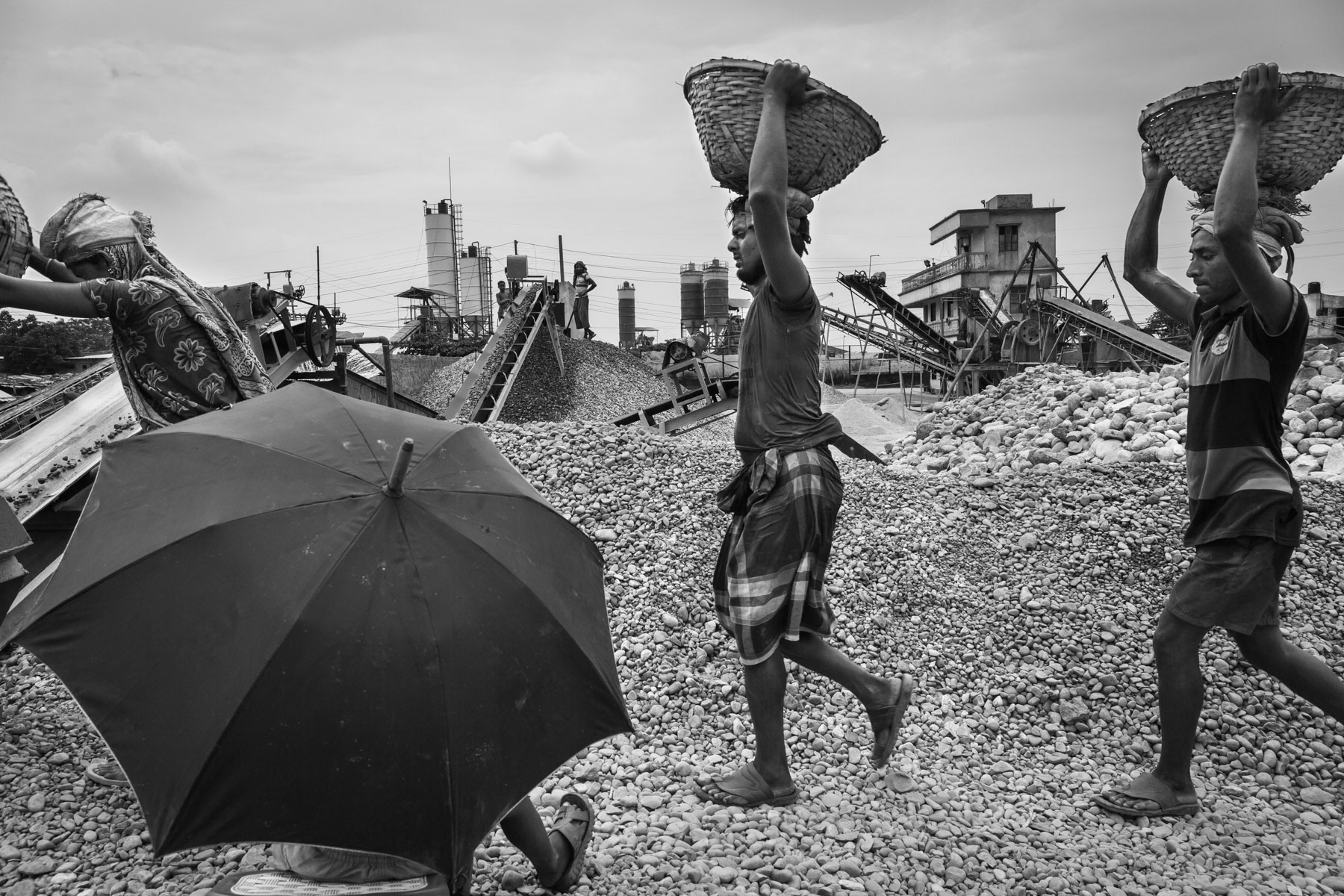 Heavy loads are generally carried on the head, cranes are seldomly used being more expensive than manual labour. Carrying daily heavy loads eventually causes fatal spinal cord injury. Stone crushing plant, Gabtoli near Dhaka, Bangladesh, May 2015