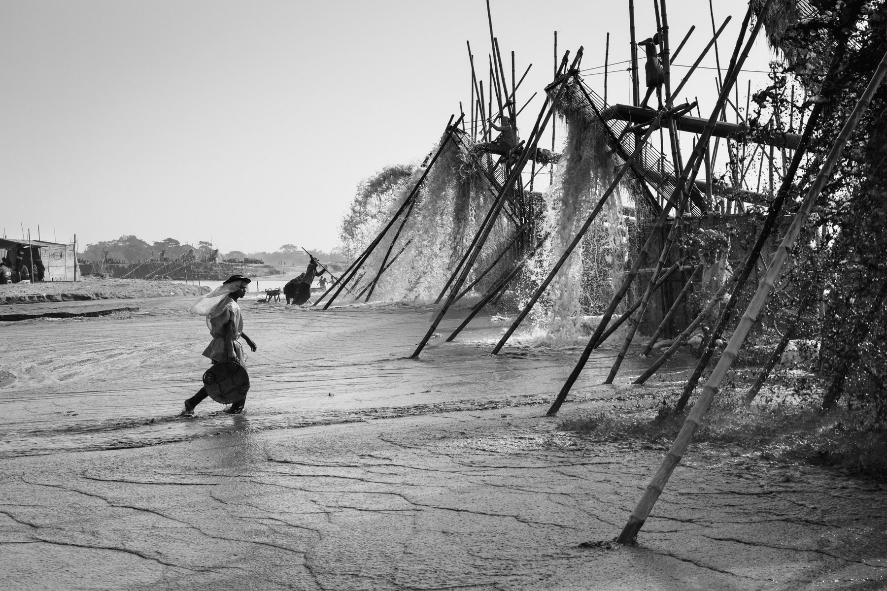 Subject of a frantic construction boom, Bangladesh is in acute shortage of sand and gravel for building purposes. The Himalayan rivers in the north of the country are being dug up during the dry season for their quality stones that will be crushed into gravel for the construction sector. Thousand of migrant workers converge to Tamabil and Bholaganj with their entire families to extract and carry stones by hand. This is the story of these women, children and men working relentlessly in extreme conditions. Extraction pumps spilling out water containing stones that are essential to supply the booming construction sector, Dholai river, Bangladesh, December 2015