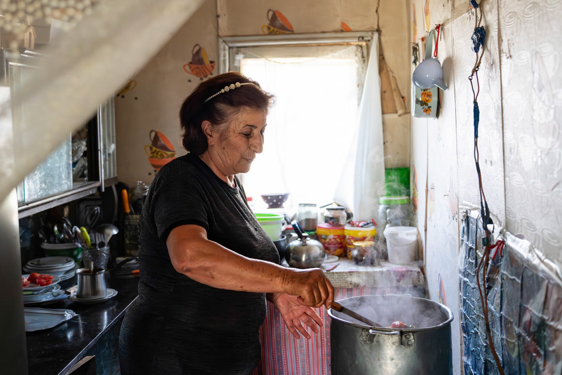 Ella is in her kitchen, preparing vegetables to preserve for the winter months. Ella and her husband have been displaced from Nagorno-Karabakh since the end of 2020, when the Lachin Corridor, which connected Armenia to Nagorno-Karabakh, came under Azerbaijani authority. Arabus, Syunik, September 2025
