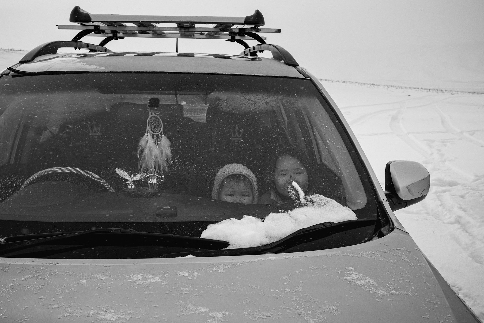 Children looking out from a vehicle, the primary link between the remote camp and the nearest town. Gobi desert, one day from Dalanzadgad, Mongolia, December 2025