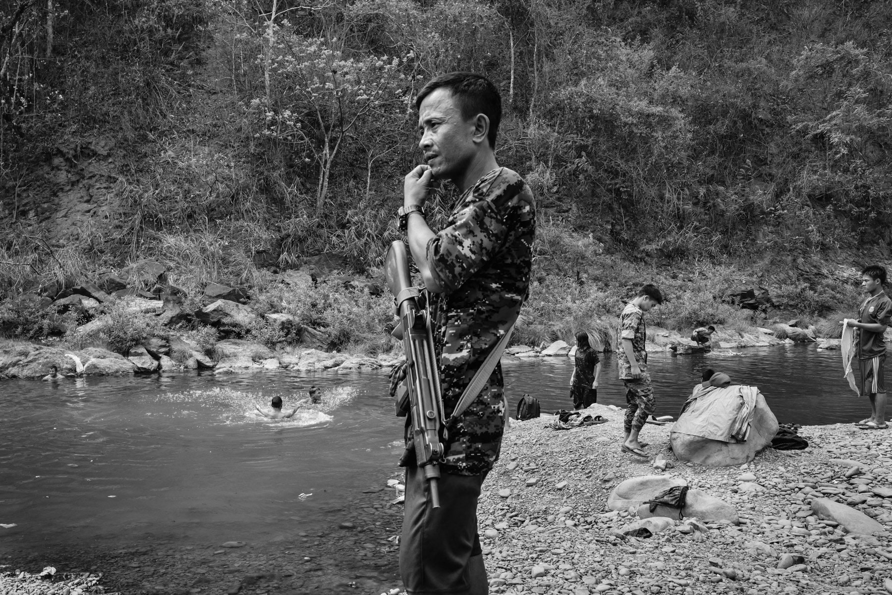 Prisoners of war (POW) bathing and washing their clothes in the river. Contrary to the Myanmar military that executes prisoners the Chin National Army provides them shelter and food and follows the Geneva conventions related to POW. Camp Victoria, Chin State, Myanmar, April 2024