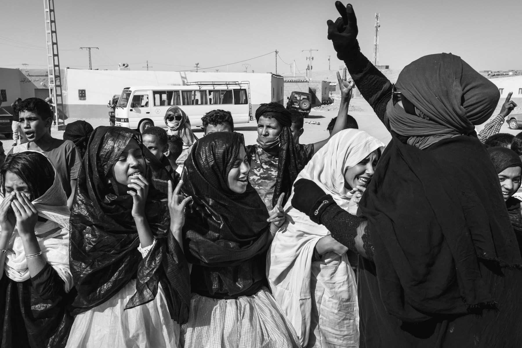 Sahrawi woman leading children and rehearsing for the ceremony of the Sahrawi 'Day of Unity', a national day on 12 October. Boujdor Saharawi refugee camp in the Sahara desert, Algeria, October 2021