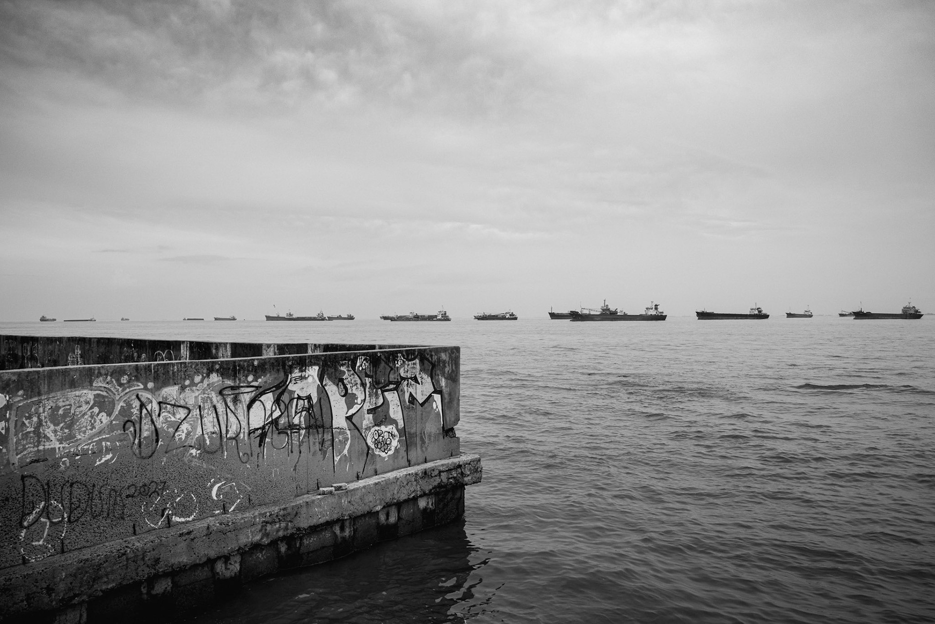 With the natural mangrove buffer gone, Jakarta’s only defense is this massive concrete barrier—a stark, artificial line against the sea. Muara Baru, Jakarta, January 2026