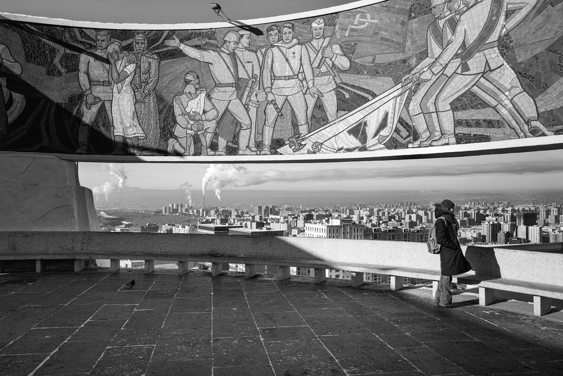 A visitor overlooks the smog-choked capital from the Soviet-era Zaisan Monument. Ulan Baator, Mongolia, December 2025