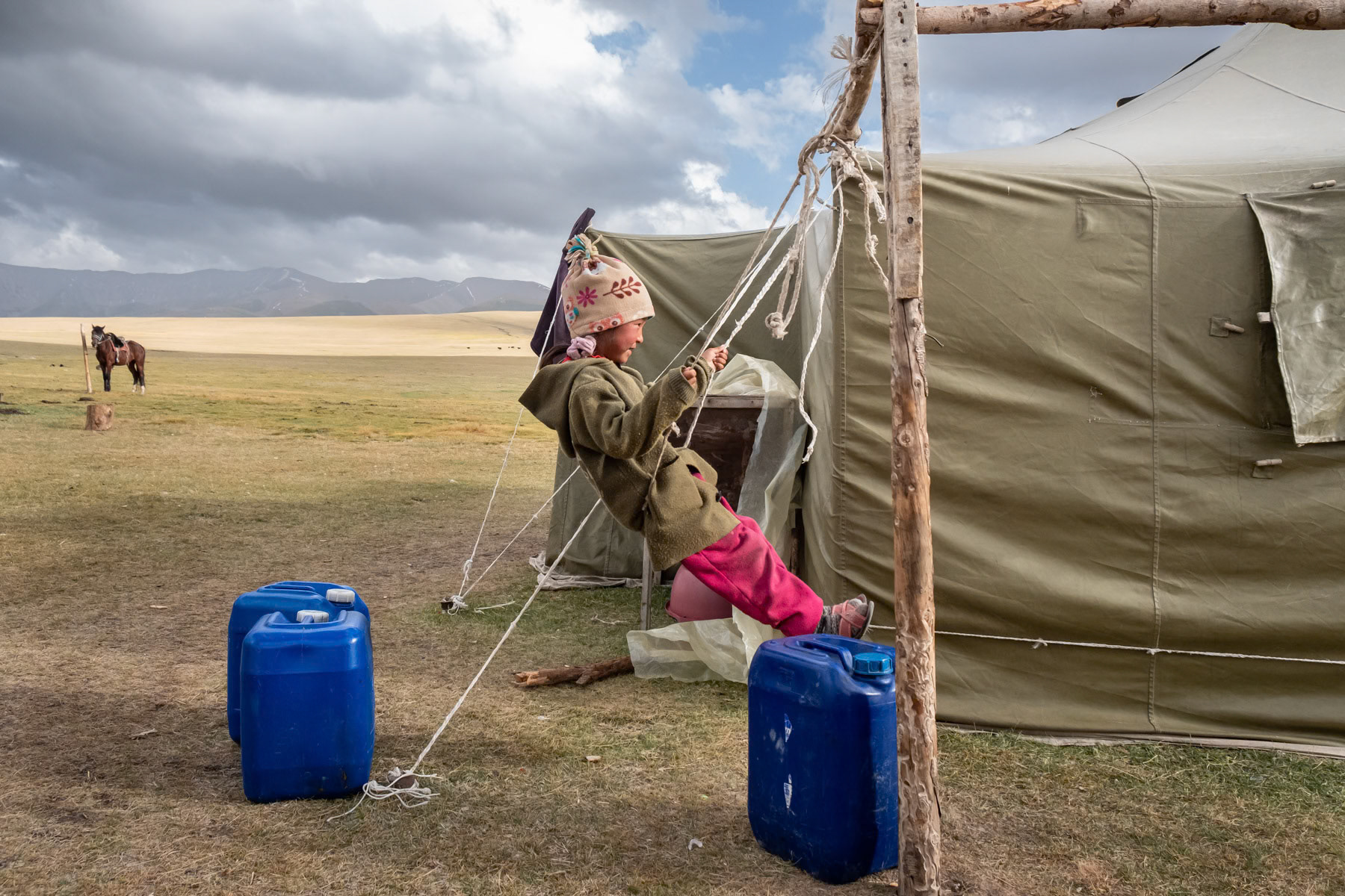 Child playing at a yurt camp where her family lives for 3 months during the summer in search of green pastures at high altitude. Son Kul Lake, Kyrgyzstan, August 2021