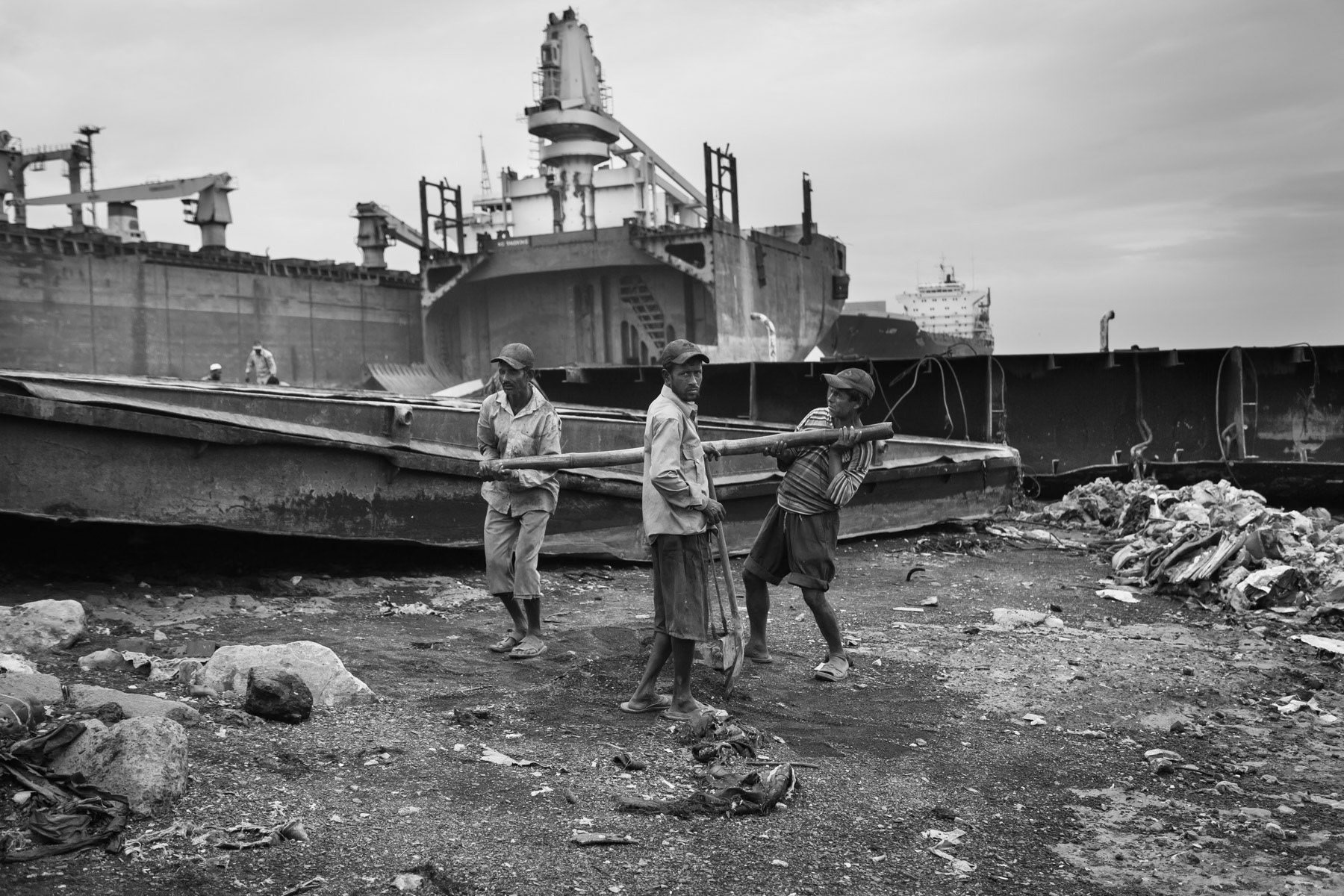 Workers carrying away ship parts. All work realted to ship dismantling is done by hand. Kumira ship breaking yards, Chittagong, Bangladesh, October 2014