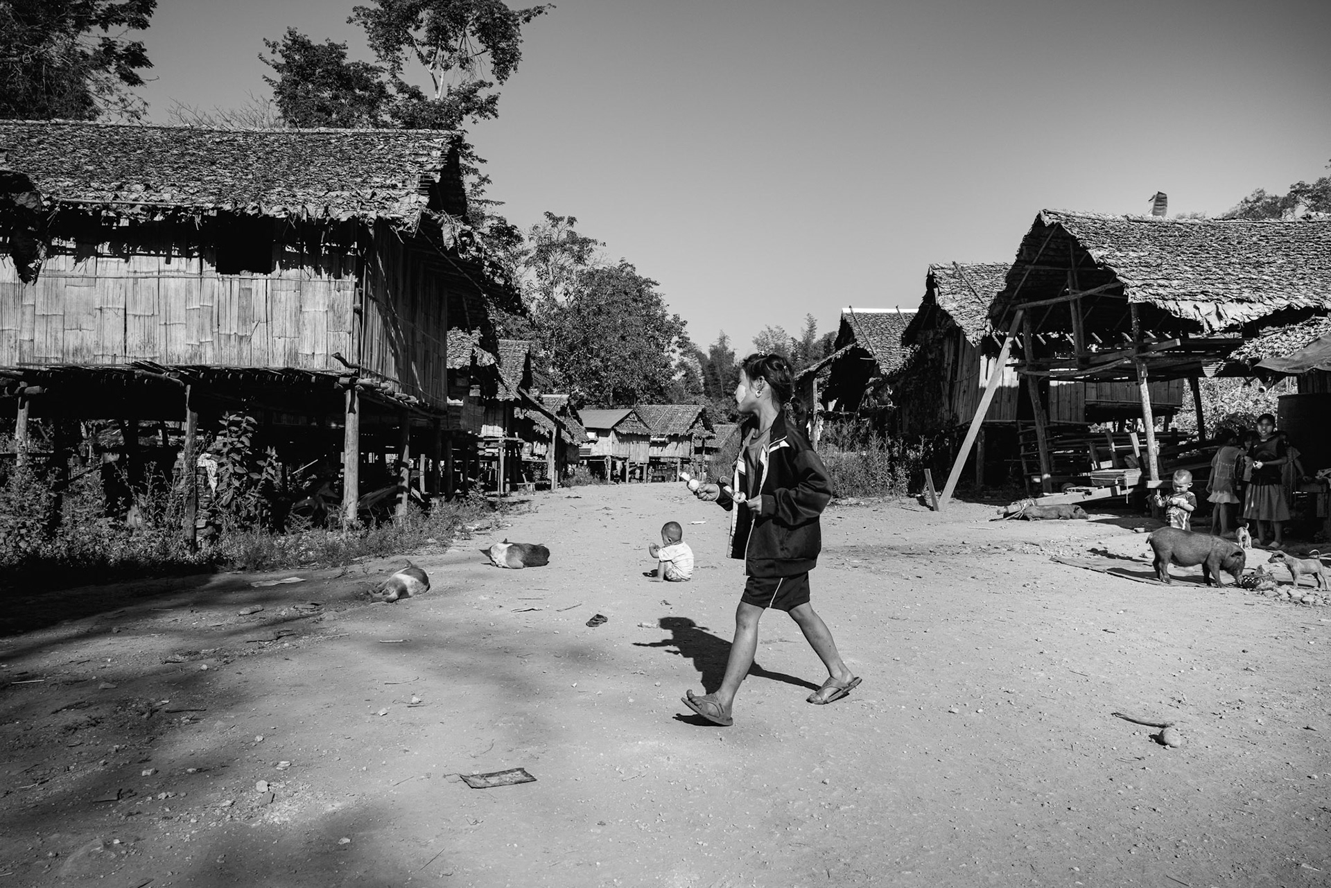 A young resident walks through the center of Kanele Htaw. For the children here, the sound of an approaching engine doesn't mean a vehicle—it often signals the arrival of a reconnaissance or attack drone. Kayin State, Myanmar, January 2026