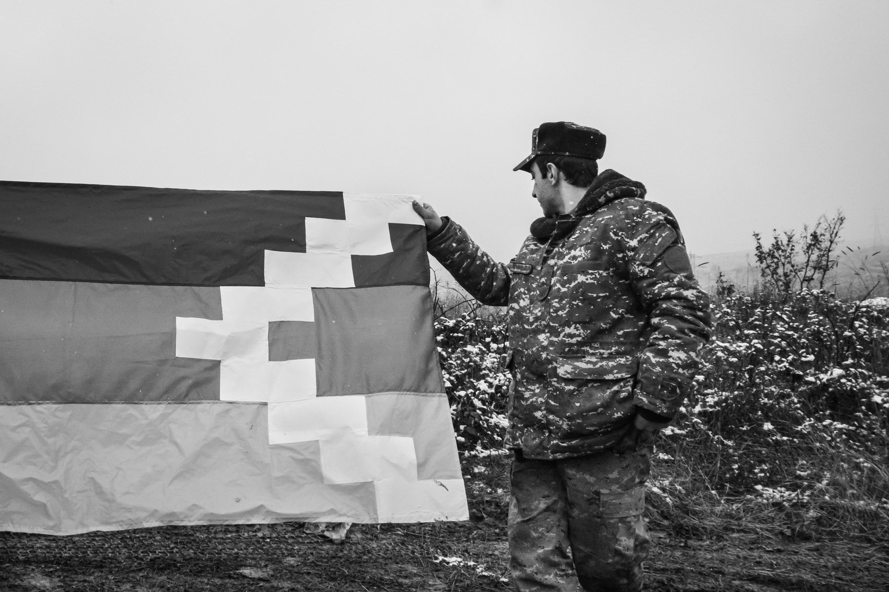 The territory of Nagorno-Karabakh and its population have been in limbo and status quo since the first war over Karabakh in the beginning of the nineties. Armenia and the self proclaimed Republic of Artsakh have for the past 27 years and the 1994 ceasefire maintained a status qu and have never really been ready to compromise with Azerbaijan on control of Nagorno-Karabakh or even the Azerbaijani surrounding territories that were occupied during the past 3 decades. The Nagorno-Karabakh frozen conflict has created divisions in the south Caucasus and isolation for Armenians. This leverage has been used by Russia in a divide and rule approach to the region ever since Stalin started ethnic, land and population engineering ninety years ago. During the past decades, Russia has been consistently arming both Azerbaijan and Armenia. While Armenia is part of a formal military alliance with Russia, this does not extend to Nagorno-Karabakh who has always been recognised as part of Azerbaijan internationally. On 27 Septamber 2020 a armed conflict between Azerbaijan, supported by Turkey, and the self-proclaimed Republic of Artsakh together with Armenia erupted in the disputed region of Nagorno-Karabakh and surrounding territories. It was the first major armed conflict, except for the 4-day April 2016 war, since the 1994 ceasefire following the first Karabakh war. The region of Nagorno-Karabakh and surrounding territories are internationally recognised as part of Azerbaijan and represent nearly 20% of its territory. Since 1994 it has however been under control and governed by Artsakh, a breakaway state with a homogeneous Armenian population. The 44-day war started with initial Azerbaijani offensives along the line of contact and gradually evolving in a massive offensive in the southern flatter parts of the region. The war was marked by overwhelming use of attack drones that took out Armenian defense lines and made a massive number of casualties before the main offensive even started. Current estimates put the current number of casualties at more than 8,000 on both sides, more than 5,000 on the Armenian side alone. The number of casualties is probably higher as many are still missing and unaccounted for. Ten thousands of civilians have been displaced within Nagorno-Karabakh and in towns close to the frontline in Azerbaijan. Widespread use of long-range artillery, missile strikes and cluster munitions on cities and civilian areas within Nagorno-Karabakh and in Azerbaijan by both sides has created another generation of displaced people in addition to the one million displaced Armenians and Azerbaijani of the first Karabakh war between 1991 and 1994. Following the capture of the southern parts of Nagorno-Karabakh by the Azerbaijani forces and Shushi, the second town in Karabakh, a ceasefire agreement was signed on 9 November 2020 between Azerbaijan, Russia and Armenia. The ceasefire agreement was mediated and sponsered by Russia and stipulates that the sides will keep control of the currently held areas within Nagorno-Karabakh, while Armenia has to return to Azerbaijan all surrounding areas it occupied since 1994. Around 2000 Russian soldiers are deployed as peacekeeping forces, for at least 5 years, along the Lachin corridor linking Nagorno-Karabakh to Armenia and within the Armenian controlled part of Nagorno-Karabakh. Without this ceasefire agreement the whole territory of Nagorno-Karabakh would probably have been overran by the Azerbaijani army, or at least its capital Stepanakert which was within 5 km after the capture of Shushi and emptied of its population by the 9th of November. Since the ceasefire and the deployment of Russian troops, Armenians have slowly started to return to the areas of Nagorno-Karabakh still under control of the Armenian authorities, faced with new geographical, military and political realities they were not prepared for. For the moment the ceasefire holds, but a comprehensive inclusive peace agreement is still very far away and the risk to enter into the same status quo as for the past 27 years is very real. It will require a lot of political and emotional courage to go beyond divisions and reconcile around things that could be of common interest. In meanwhile the presence of peacekeeping troops will guarantee a status quo but not peace. Armenian soldier holding the Artsakh flag. Artsakh is for Armenians the territory of Nagorno-Karabakh and surrounding captured lands during the first war between 1991 and 1994. The self proclaimed Republic of Artsakh was never recognised internationally. Southern frontline road between Karmir Shuka and Chartar, Nagorno-Karabakh, December 2020