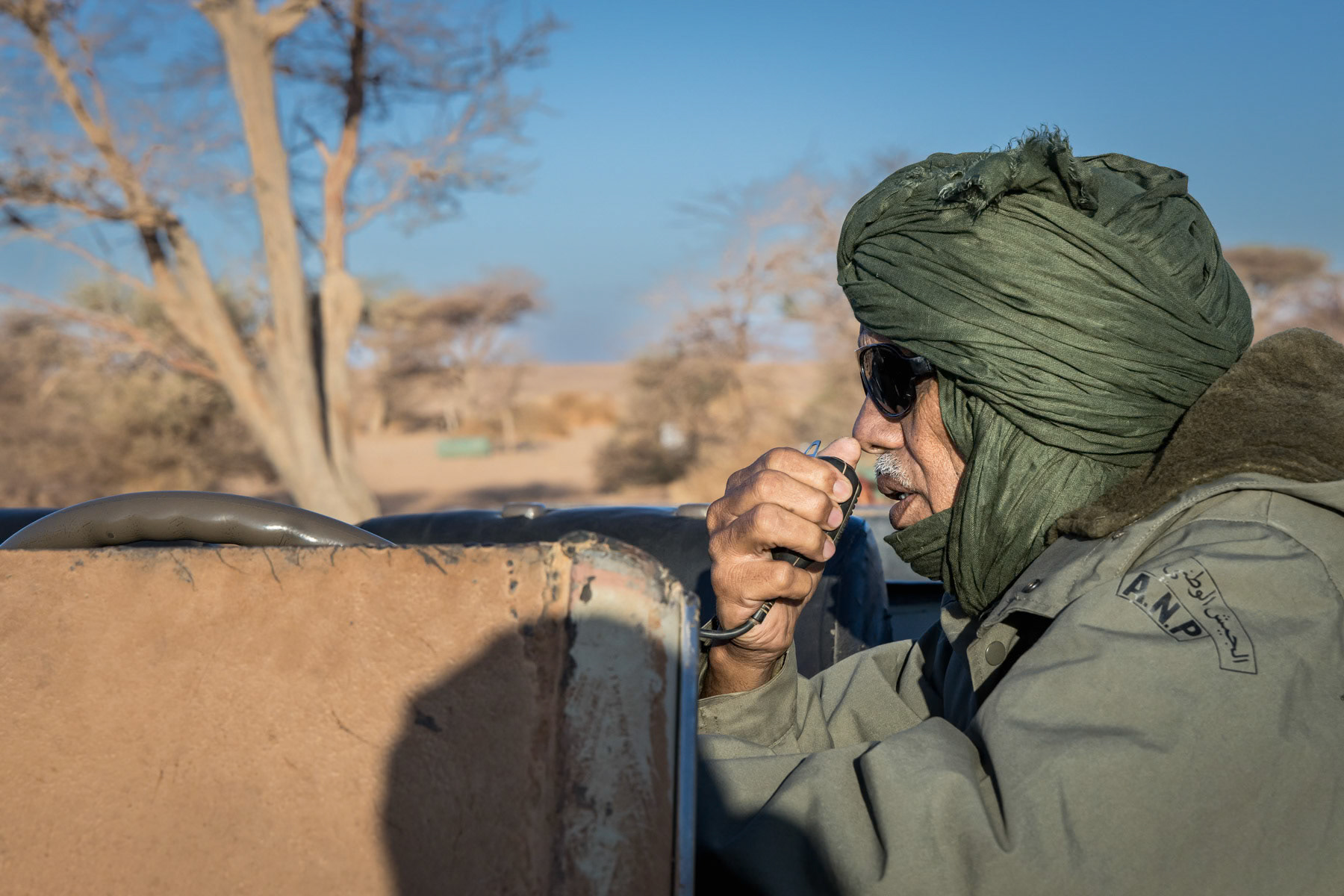 On 14 November 2020, the Sahrawi Arab Democratic Republic (SADR) president Brahim Ghali announced that he signed a decree bringing the 29 year old ceasefire to an end, citing an incident 2 days earlier in which Moroccan armed forces forcibly entered a crossing within the buffer zone that was being blocked by Sahrawi protesters, acts which the SADR considered a declaration of war. Since then the Polisario Front, the armed branch of the SADR, has been launching attacks against Moroccan positions along the 2,700 km sand wall that divides the territories controlled by Morocco since the 1991 ceasefire and the remaining 20% of the territory controlled by the SADR. Being outnumbered the Polisario Front uses highly mobile units to attack and adopts guerilla techniques while Morocco has numerous troops engraved in bunkers along the sand berm forming the frontline. The Moroccan army has also started tu use attack drones further complicating the Polisario's mobility capacity in this huge desert battlefield. Sahrawi military commander communicating with his untis on the frontline near the 2,700 km long sand berm, built by Morocco, dividing the Western Sahara between the Moroccan controlled territories and Sahrawi liberated territories. Mobile camp in the desert in the northern second military region, Sahrawi Arab Democratic Republic, October 2021