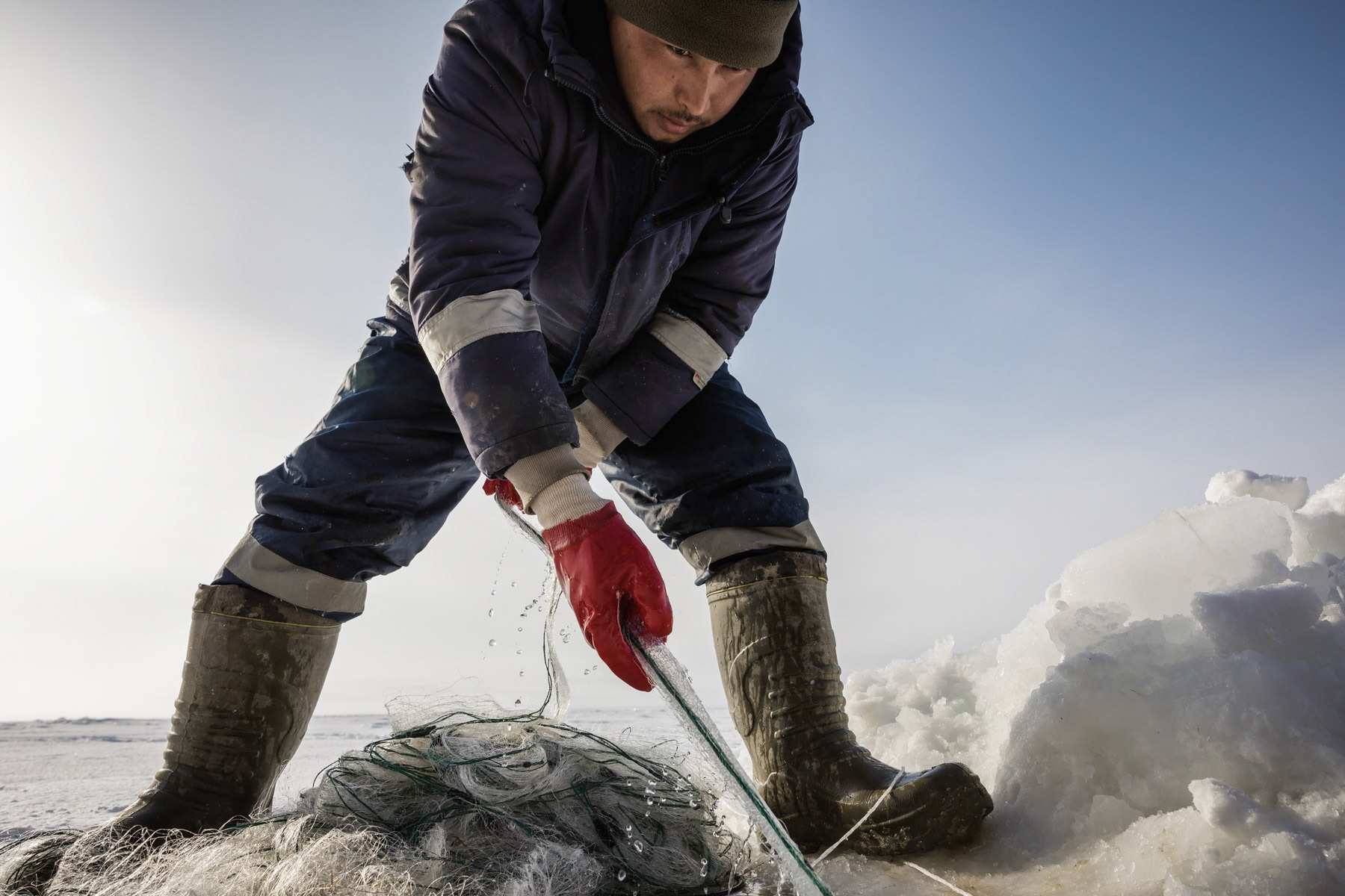 A fisherman fetching the net through the hole in the ice. Aral Sea, Kazakhstan, January 2019
