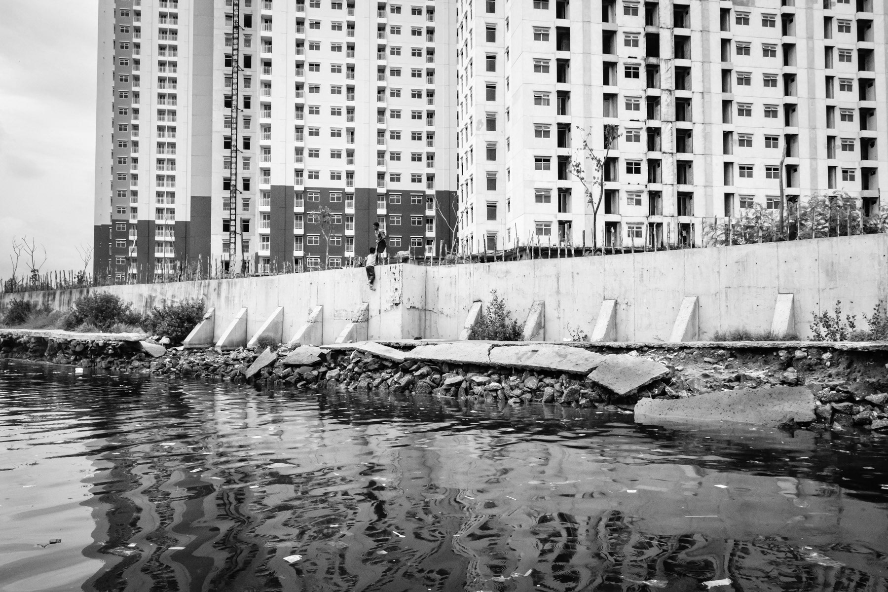 Muara Buru a neighbourhood along the seashore is partly protected by a sea wall against rising sea levels and sinking soil. The soil is sinking at a rate of 10 to 20cm per year. The unstability of the ground is provoked by widespread drilling of water wells for new real estate projects, creating huge air pockets once the water is exhausted. North Jakarta, Indonesia, March 2020