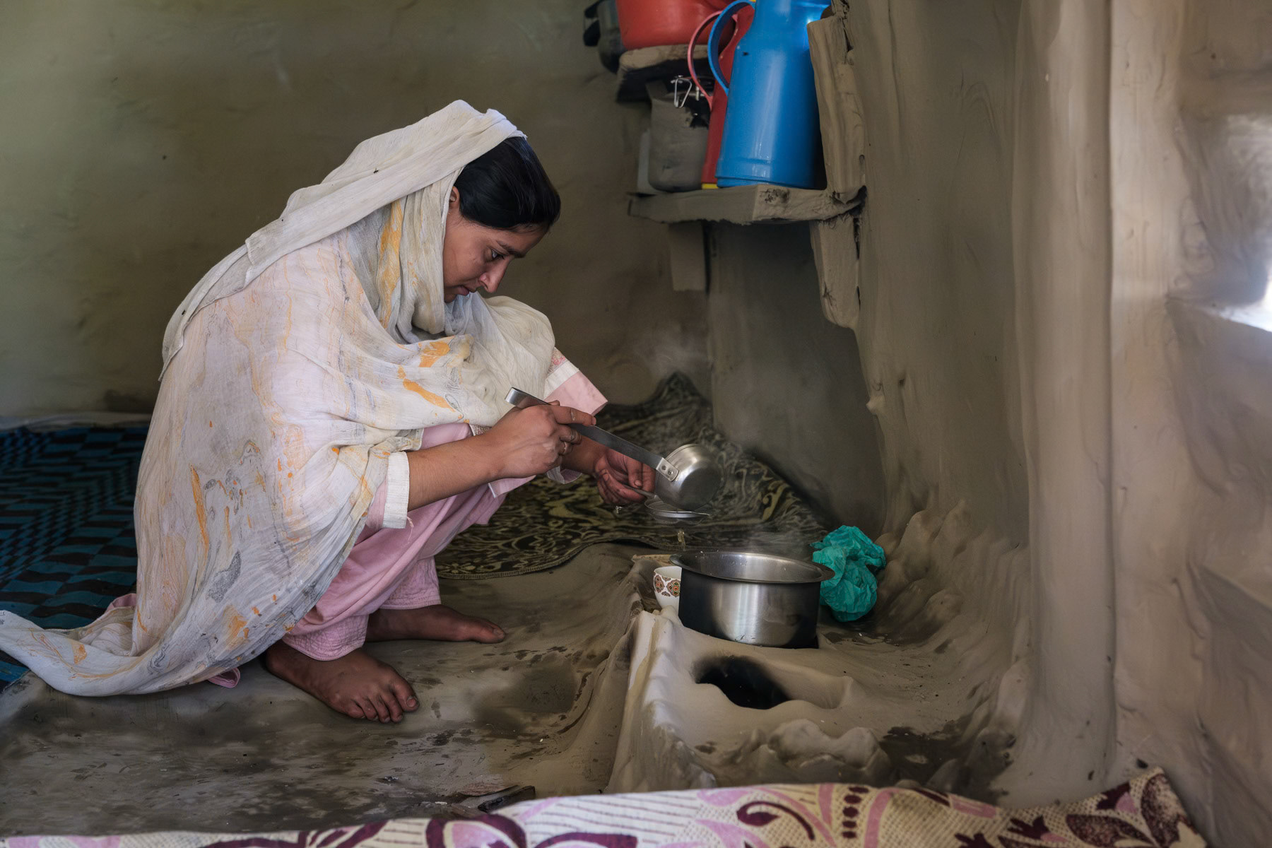 Kashmiri woman preparing coffee on a traditional mud stove. Naranaag mountains, in Indian Administrated Kashmir, September 2023