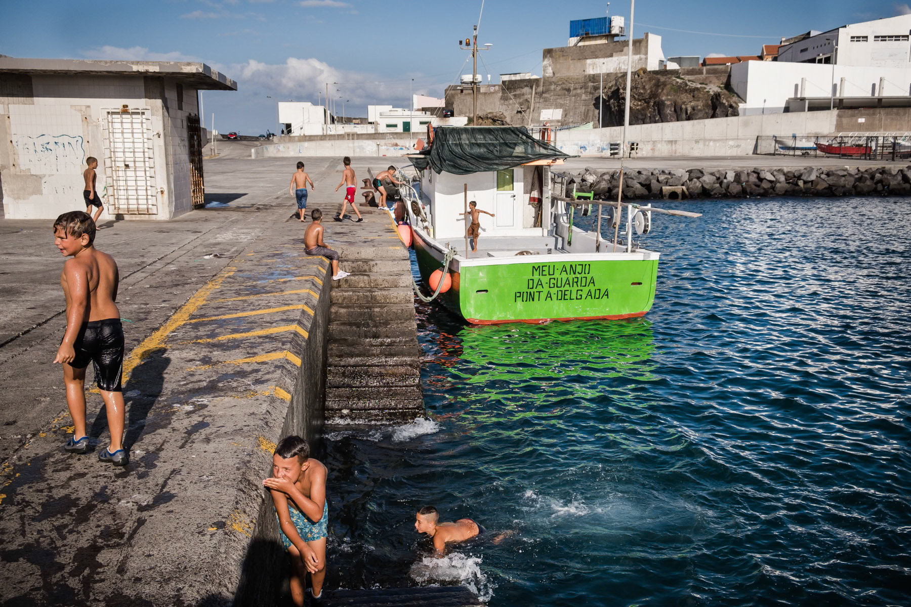 Kids playing and swimming in the port. Rabo de Peixe, Azores, September 2018