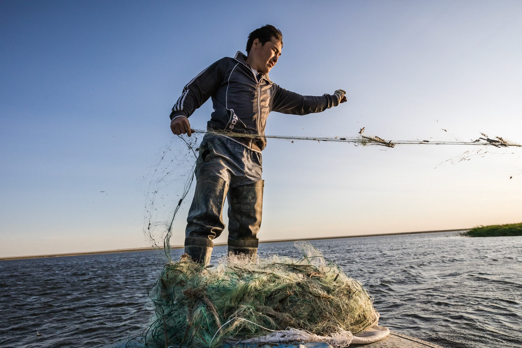 Fisherman throwing the fishing nets in the Aral Sea. Akbasty, Kazakhstan, June 2019