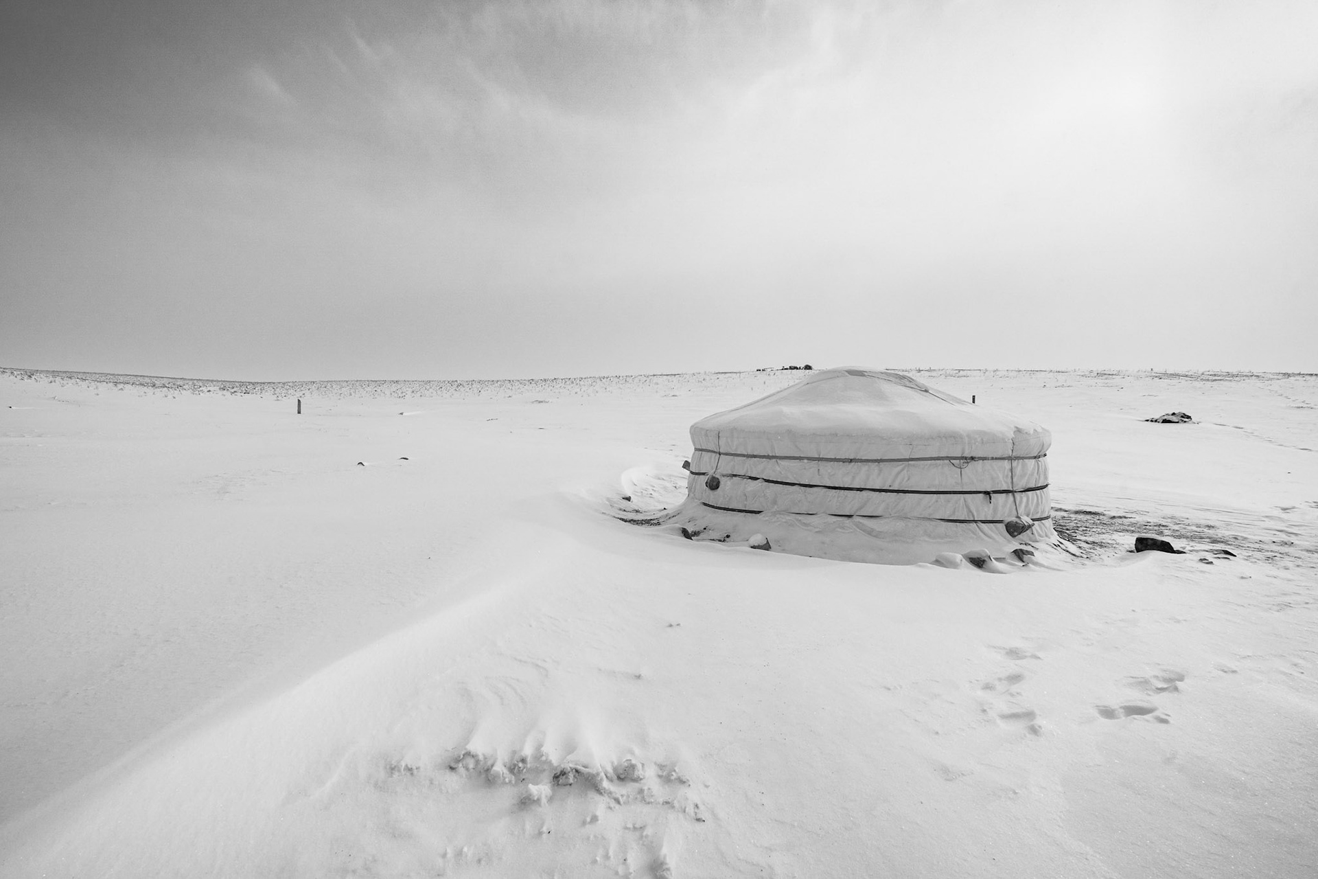 A Ger stands as a solitary defiant shape against a horizontal world of snow. Gobi desert, Mongolia, December 2025