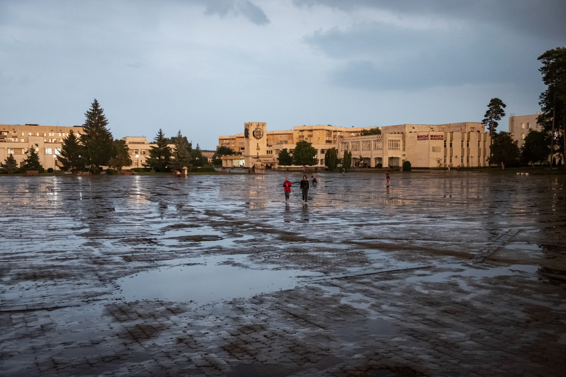 Main square of Slavutych, a town of 20,000 people that was build between 1987 and 1990 to accomodate people evacuated from Pripyat and the Chernobyl exclusion zone. It was buid with large green spaces and micro district contributed and constructed by other Soviet Repubilcs (Estonia, Lithuania, Latvia, Georgia,Russia, Belarus, Armenia and Azerbaidjan) As of 1989 the further extension of the town stopped as funds were re-directed towards Armenia following the 1988 earthquake and eventually stopped completely with the collapse of the USSR. Since 2000 and the closure of the last working nuclear reactor of the Chernobyl NPP, the number of habitants has constantly decreased from about 30,000 in the nineties to 20,000 now. The majority of working age residents work in the Chernobyl exclusion zone and the nuclear power plant. Slavutych, Ukraine, August 2021