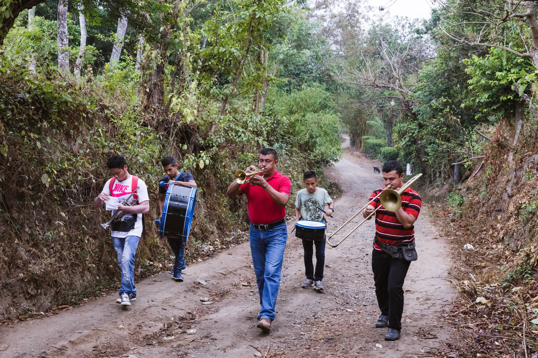 A local music band visiting villages before Easter celebrations, El Almendro village, El Salvador, April 2019 Migartion from El Salvador is shaped by a legacy of civil war, deeply rooted social inqualities, violence and climate change. El Salvador and its population of 6.4 million is the smallest Central American country, yet the most densely populated of the region. A post-conflict stagnant economy, natural and climatic disasters and high levels of violence have pushed growing numbers of people to leave over the past 3 decades. Most by far make their way to the U.S. where nearly 1.5 million El Salvadorans live. Persistent social unrest erupted into open conflict by the mid-1970s, culminating in a bloody civil war between 1980 and 1992. The U.S. played a pivotal role by providing enormous levels of funding, military aid, advisors and training to the right-wing government in power. The conflict displaced roughly one fifth of the population and some 75,000 people were killed during the war in addition to the thousands who were tortured and disappeared. More than 85% of these atrocities were committed by government troops supported by the U.S., according to a U.N. Truth Commission report. After the war the unequal economic system remained basically the same resulting in worsening living conditions and widening inequalities in an economy artificially sustained by remittances from the ever growing Salvadoran migration abroad. Today, levels of violence are even higher than during the civil war in certain areas and have affected entire communities. The overwhelming majority of victims being the poor working class Salavadorans who must live and conduct their lives in some of the most dangerous areas and who cannot afford private security companies to protect them. This situation contributes at maintaining a large flow of Salavadorans leaving the country. Climate change and natural disasters is also a reason why Salvadorans leave there country. Repetitive droughts and rising temperatures have substantially altered agrarian practices pushing large portions of the rural population towards the city and eventually immigration. El Salvador is a large coffee producer, in recent years coffee producers have more and more difficulties to cultivate the coffee at what were once normal altitudes between 800 and 1200m. Because too high temperatures coffee is being cultivated at higher and higher altitude, even above 2000m with as result higher production costs and less available land. With falling world prices, more and more Salvadorans have to abandon coffee production as moving higher in the mountains is not possible for all involved in the coffee production. People leave, memories stay.