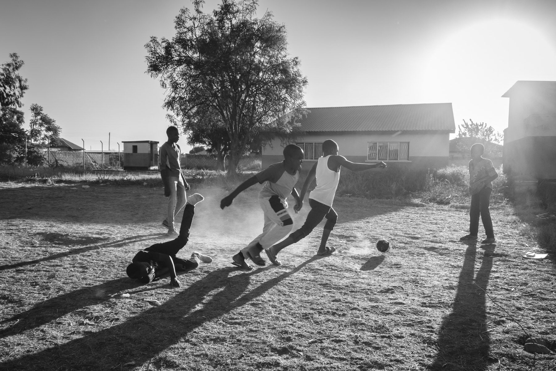 Kabwe, a mining city in central Zambia of 300,000 habitants, has a century old history of lead and zinc mining and smelting. From 1925 to 1974 exploited by Anglo American Mining Industry and after the country's independence by the Zambian State until the main mine's closure in 1994. Kabwe is nowadays one of the most soil polluted places on earth with residual toxic particles in the ground. While in operation there no pollution laws regulating emission from the mine and smelting plants. The fumes containing life-treathening levels lead particles fell and sunk slowly into the soil in and around the city where large communities are living. Furthermore at the time of partial closure in 1994 there was no clean up and soil decontamination process. Analysis carried out with support of the World Bank has shown that lead pollution in Kabwe is still extremely high and not enough has been done in remediating the situation in the most affected communities. The amount of lead particles in the soil is estimated to be at least 10 times above internationally approved safety limits and even higher in hotspots like the Kasanda neighbourhood where miners live beside the mining complex.The vast majority of children have levels of lead in their blood well above the safety limits, and causes brain, liver and hearing damage among other, in extreme cases death is the likely outcome. Children in young age are particular vulnerable as they have the tendency to swallow the most when playing outside and frequently put their hands to their mouth. Nearly 75% of children in Kabwe would need medical treatment to remove metals and minerals from their body. Over 100,000 children and women in child-bearing age could have been exposed to severe lead poisening. High unemployment in the Kabwe, pushes people to resort to scavenging or small scale artisanal mining for lead or zinc and as such continues the expansion of polluted areas and soil degradation. Children playing in Kasanda Mine neighbourhood, one of the most contaminated areas in Kabwe. The soil in and around the city of Kabwe contains life-threatening levels of soil particles containing lead. The amount is estimated to be 10 times above WHO safety limits and even much higher in hotspots. Children are particulary vulnerable as they have the tendency to swallow the most when playing outside in a dusty environment. Kabwe, Zambia, May 2021