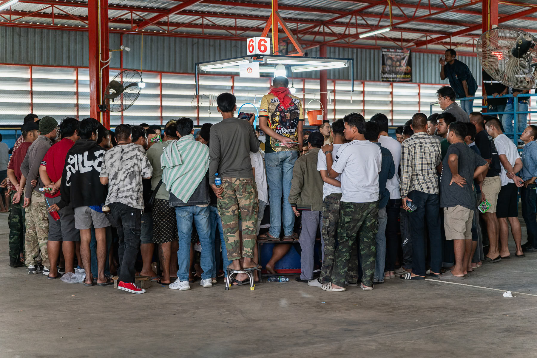 Spectators watching and betting on a rooster fight. Kanchanaburi, Thailand, January 2025