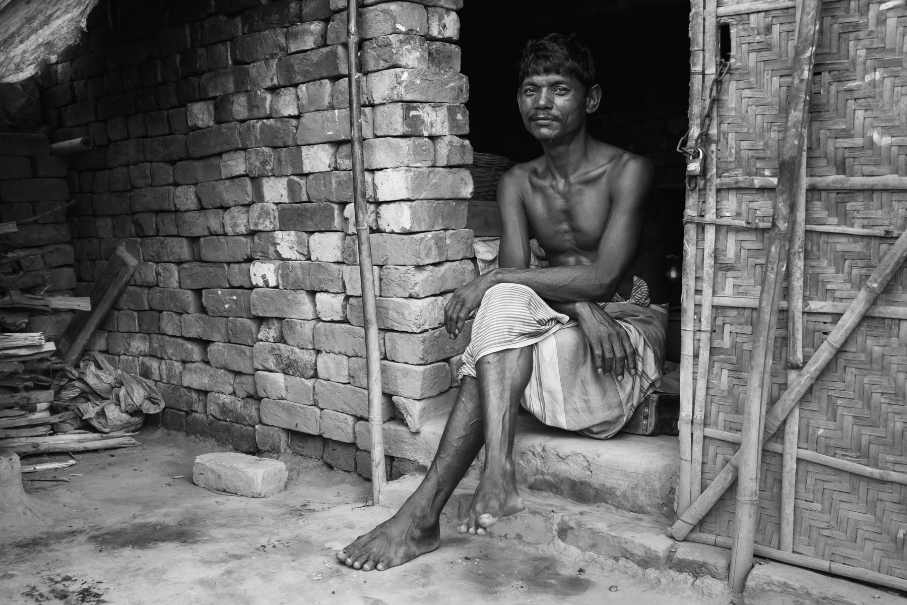A worker at the end of the day in front of his shelter on the brick fields in Barera near Mymensingh, Bangladesh, May 2015