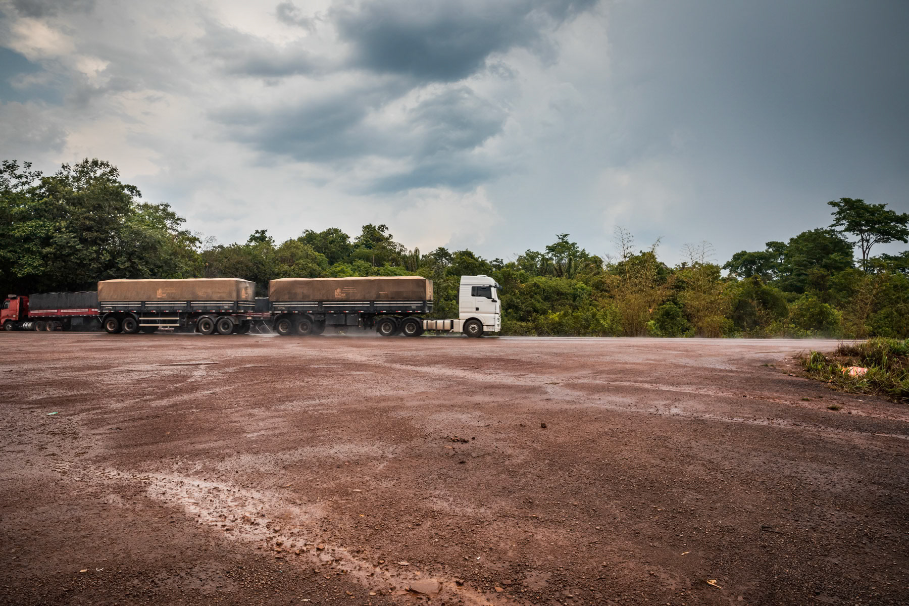 Trucks transporting soybeans to the port of Santarem along the main road BR163. BR163 is one of the 3 developped roads cutting through the Amazone linking it with Mato Groso and part of the deforestation arc or green frontlines. The State of Para is now victim of massive deforestation in order to expand monoculture and cattle farming beyong Mato Grosso well into the Amazon. Usually 50 km on both sides of a new route are fully cleared through the years and vegetation is replaced by industrial farming. Para State, Brazil, October 2020