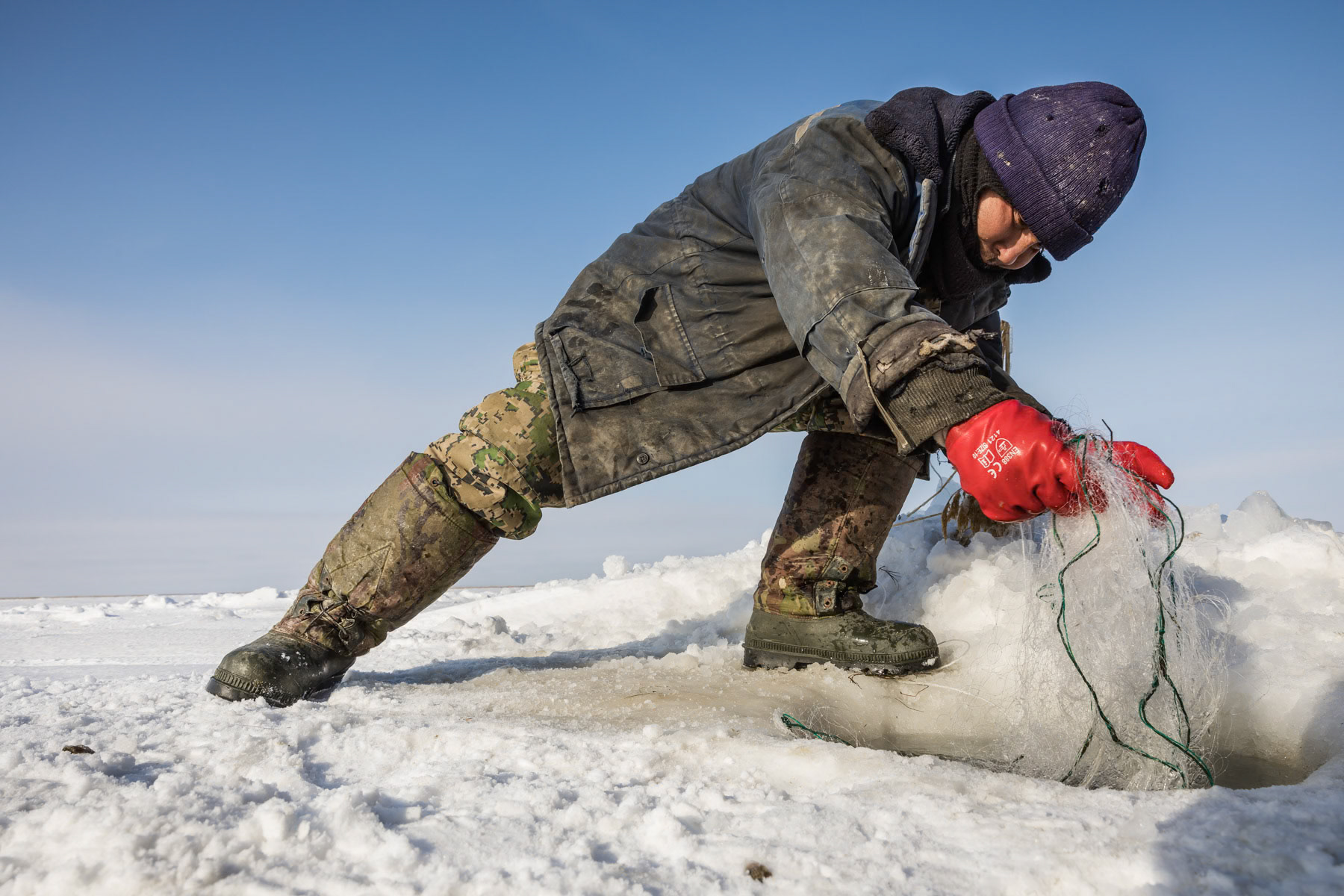 A fisherman fetching the net through the hole in the ice. Aral Sea, Kazakhstan, January 2019