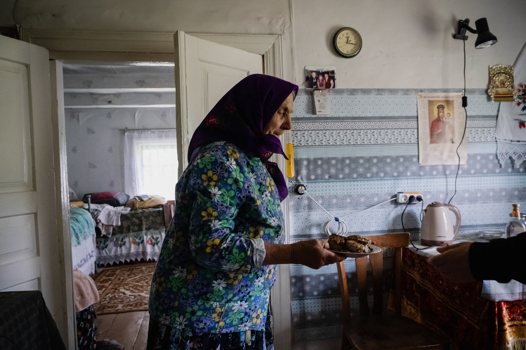 Gania (Hanna) is 88 years old and has always lived in Kupovate village except for 18 months when she was evacuated after the nuclear reactor explosion in 1986. She worked in a local kolhoz (a collective farm during Soviet time) as a cow milker and other farm works. She lived with her sister, who passed away 6 months ago and her husband who died 10 years ago. All a buried here and she has no intention to move out of the exclusion zone and live with her daughter in the city. Kupovate, Chernobyl exclusion zone, Ukraine, June 2021