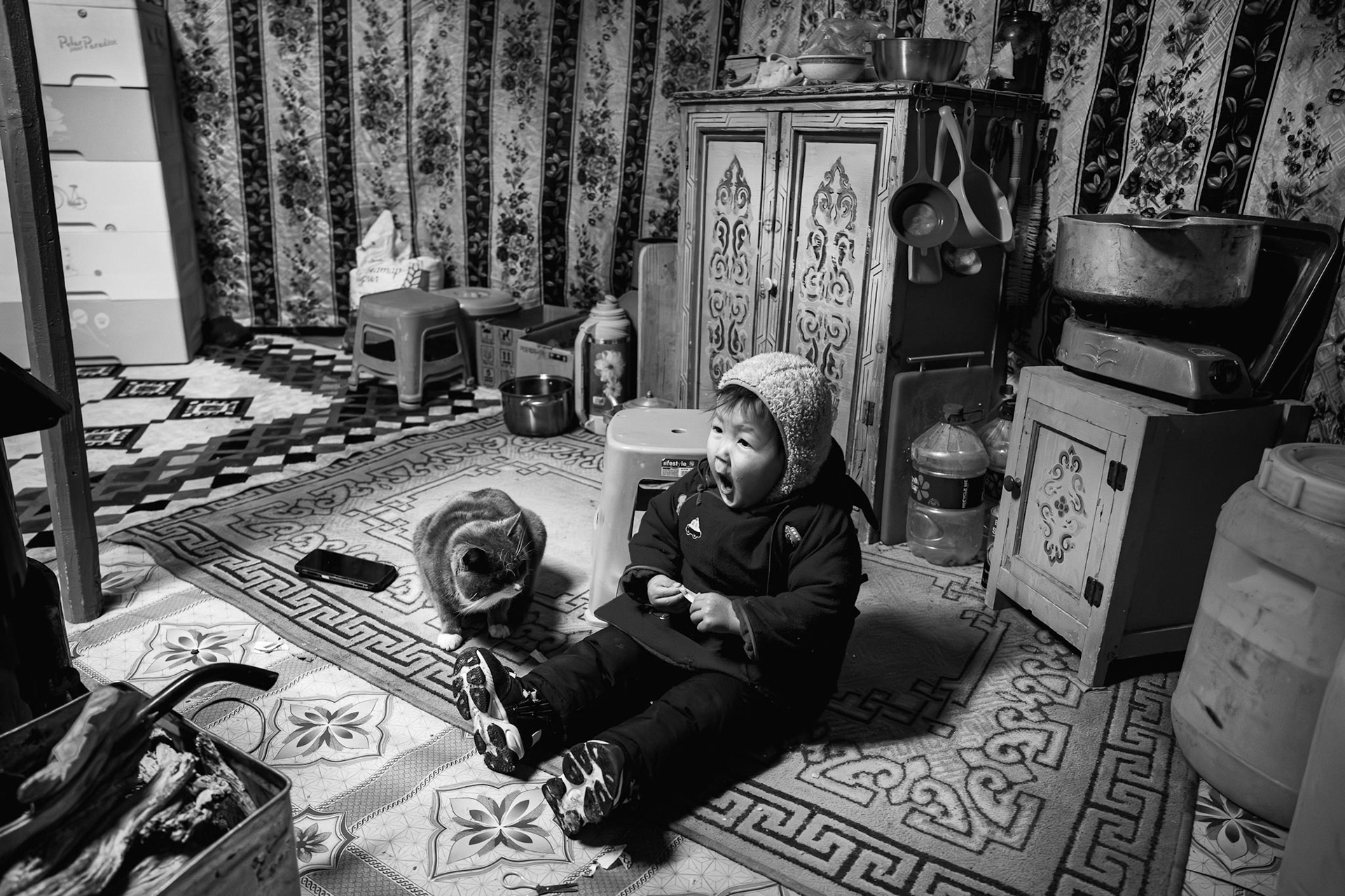 A young child sits by the stove, which provides the only heat against the brutal December cold. Gobi desert, Mongolia, December 2025