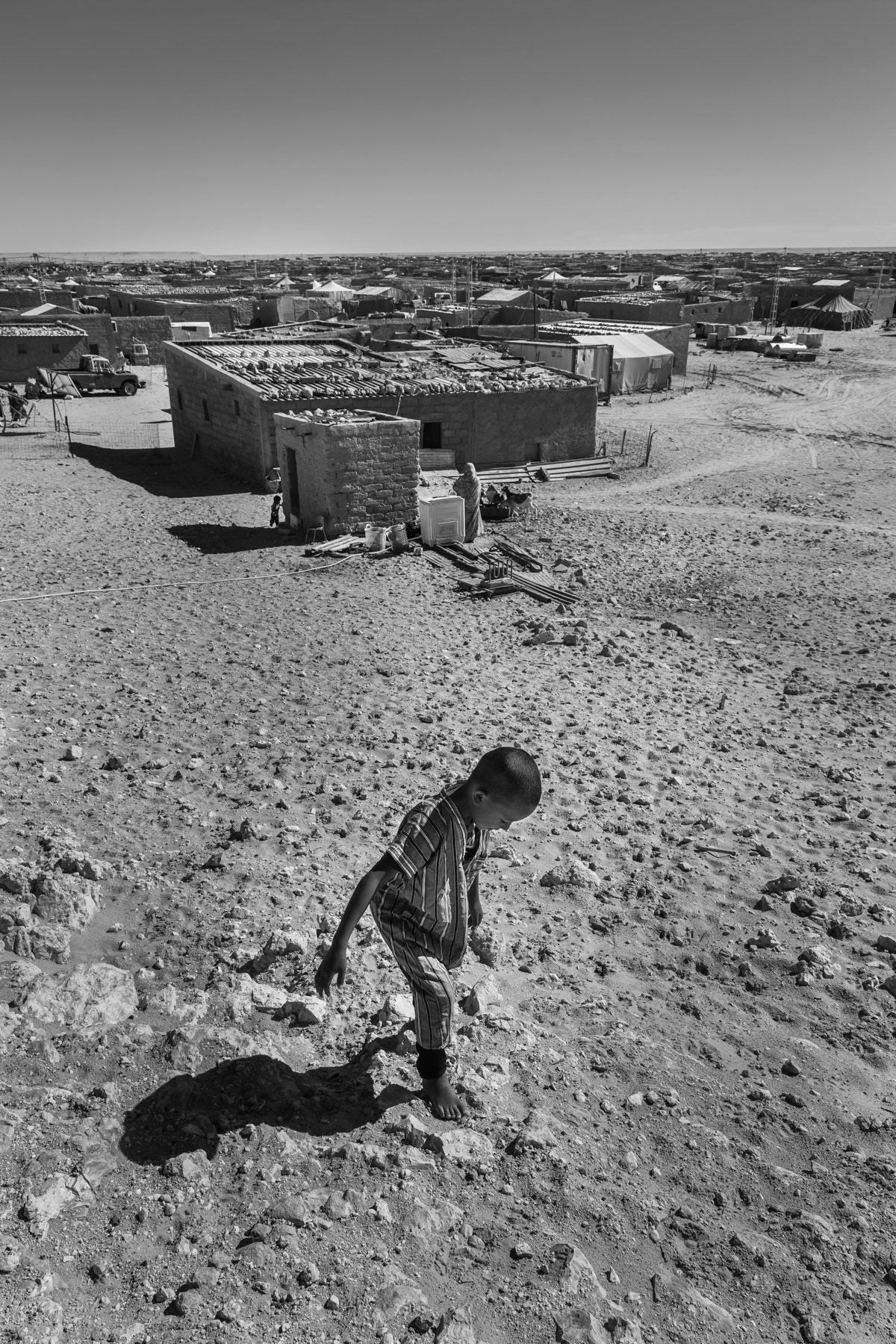Saharawi child playing on a sand dune overlooking Smara refugee camp. Saharawi refugee camps were established in the seventies in an area managed by the POLISARIO, the government in exile of the Saharawi Arab Democratic Republic (SADR). Between 120 and 150,000 refugees from the Western Sahara live in 5 refugee camps in the desert south of Tindouf. Smara Refugee Camp, Algeria, December 2019