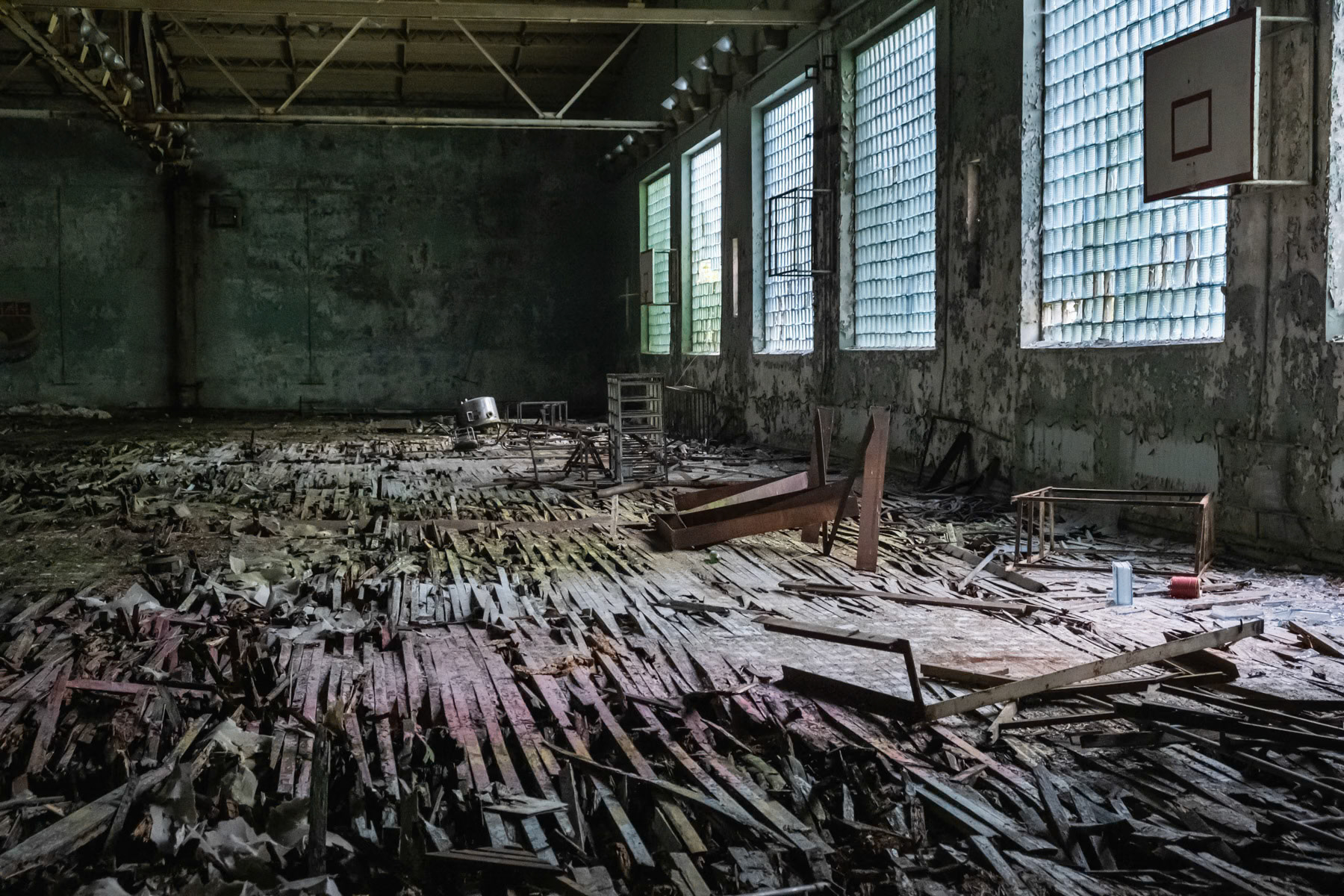 School sporthall in Pripyat town. The town was developed alongside the nuclear power plant to house staff and their families. Before the disaster it consisted of 5 districts, each of them with well-developed infrastructure. There were 5 schools, 14 kindergartens, a cinema, swimming pools, theatre, shopping centres and residential buildings for 30,000 people with extensions planned of at least one more district near the port area. The complete population of Pipyat was evacuated 36 hours after the disaster to never return again. Pripyat is now an overgrown ghost town where time stood still on 27 April 1986. Pripyat, Chernobyl NPP, Ukraine, June 2021
