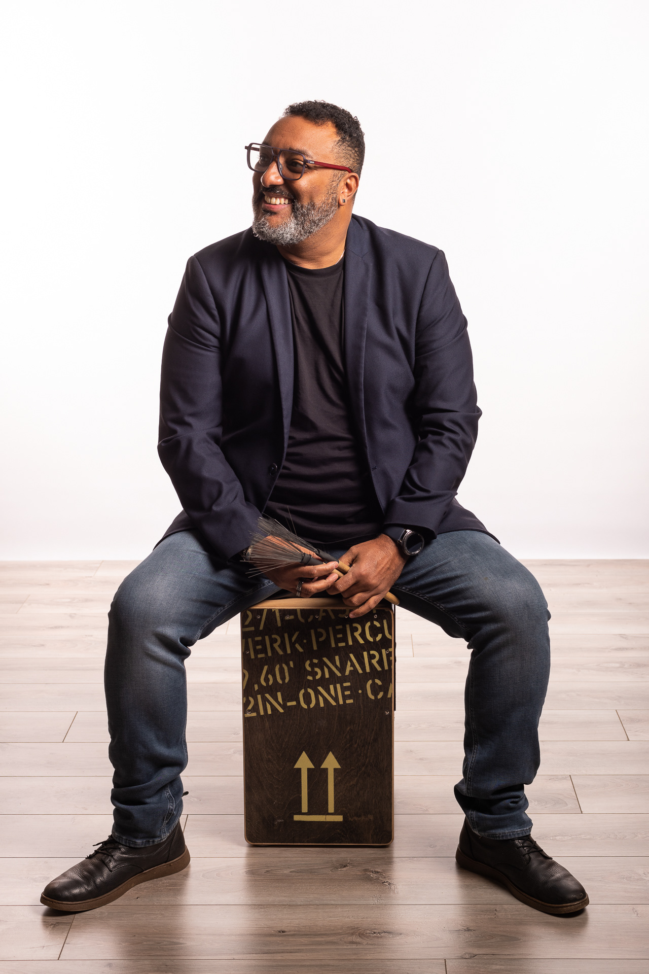 Votre photographe luman Baremond , souriant assis sur un Cajon ( instrument de musique )
