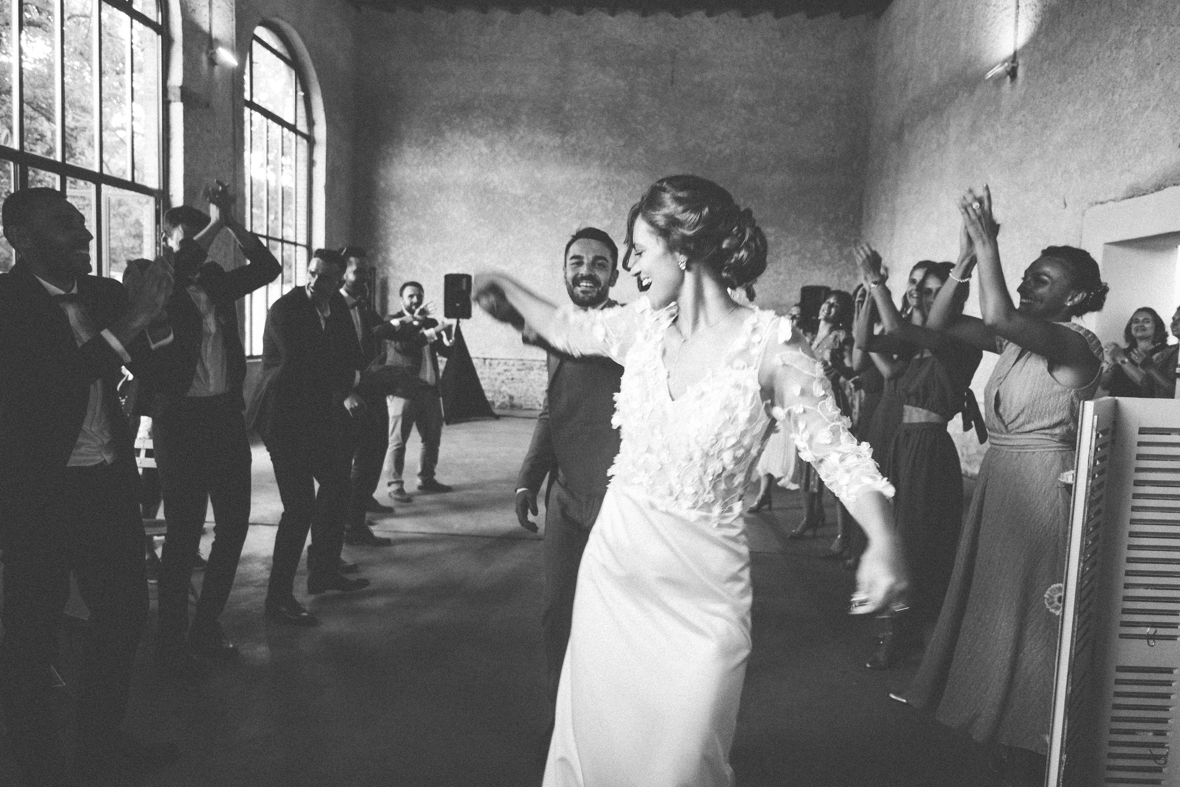 une mariée et un marié dansent devant les invités de leur mariage , photo en noir et blanc