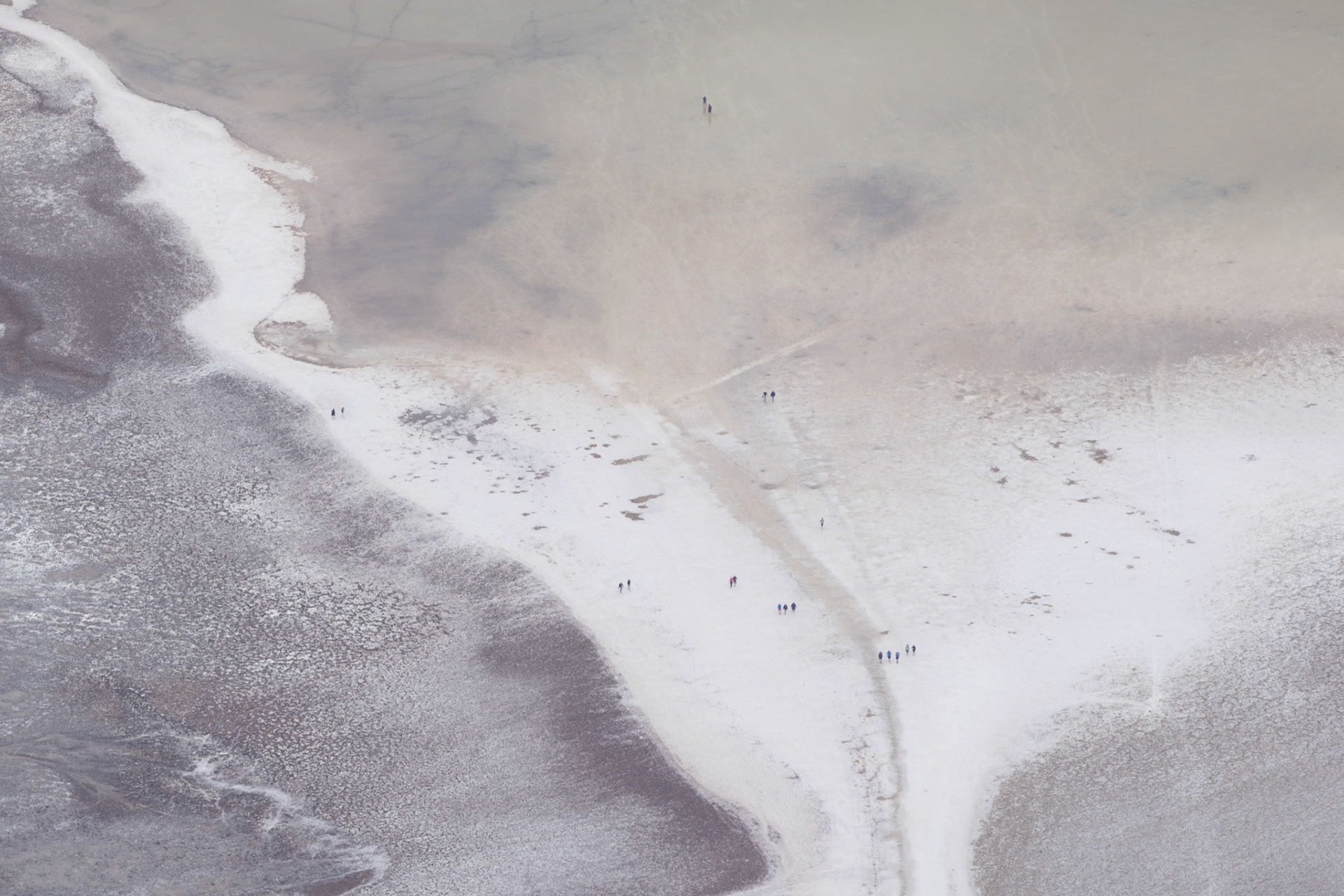 Detail of the edge of Lake Manly with hikers along the waters edge and wading in the water