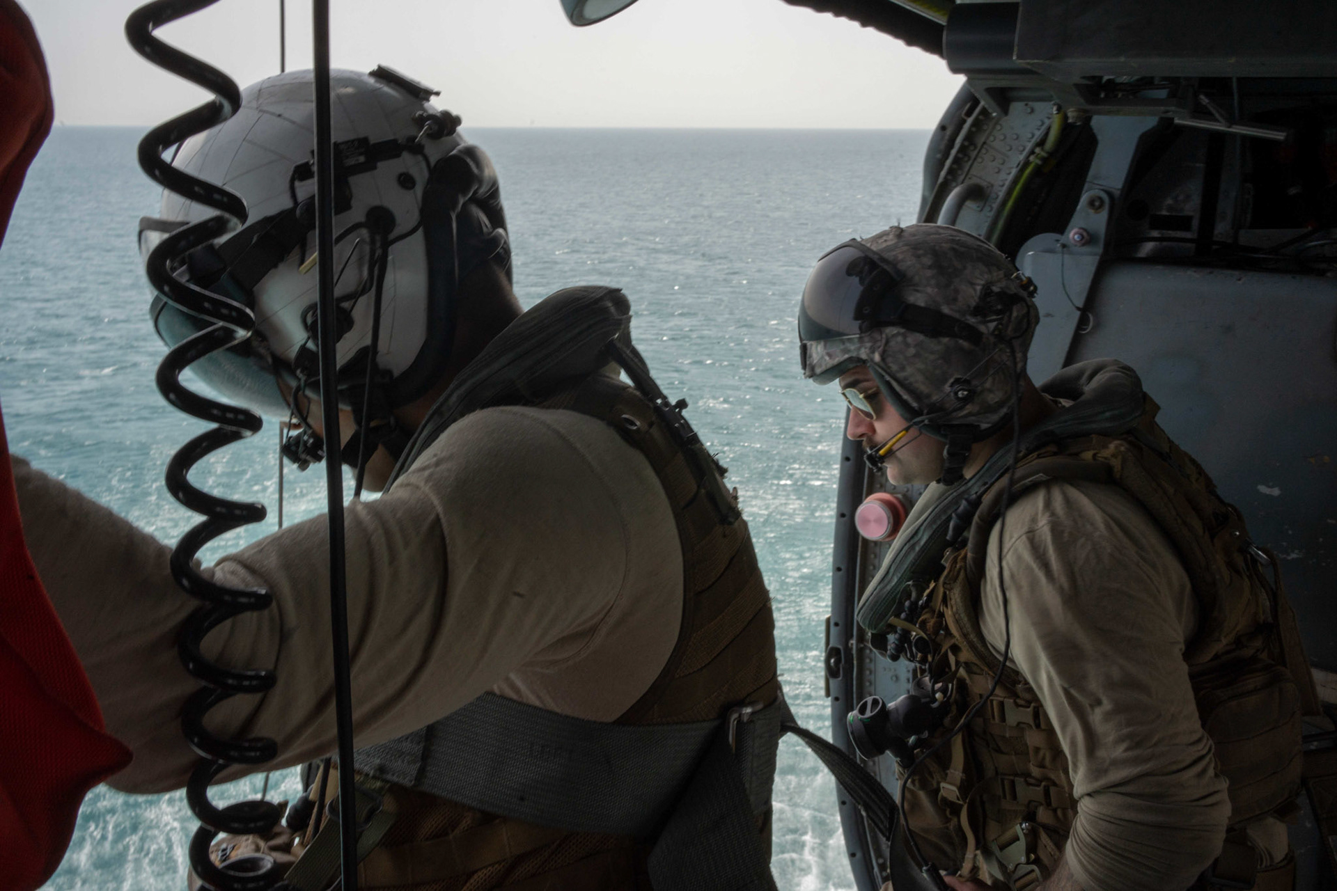 220511-A-YK067-1032 ARABIAN GULF (May 11, 2022) Naval Aircrewman (Helicopter) 2nd Class Hunter Hill, left, and Lt. Evan Sternstein, assigned to Helicopter Sea Combat Squadron (HSC) 26, fly in an MH-60 Knighthawk during an at-sea search and rescue training operation during Exercise Neon Defender 2022. Neon Defender is an annual bilateral training event between U.S. Naval Forces Central Command and Bahrain. The exercise focuses on maritime security operations, installation defense and medical response. (U.S. Army photo by Sgt. Terry Vongsouthi)