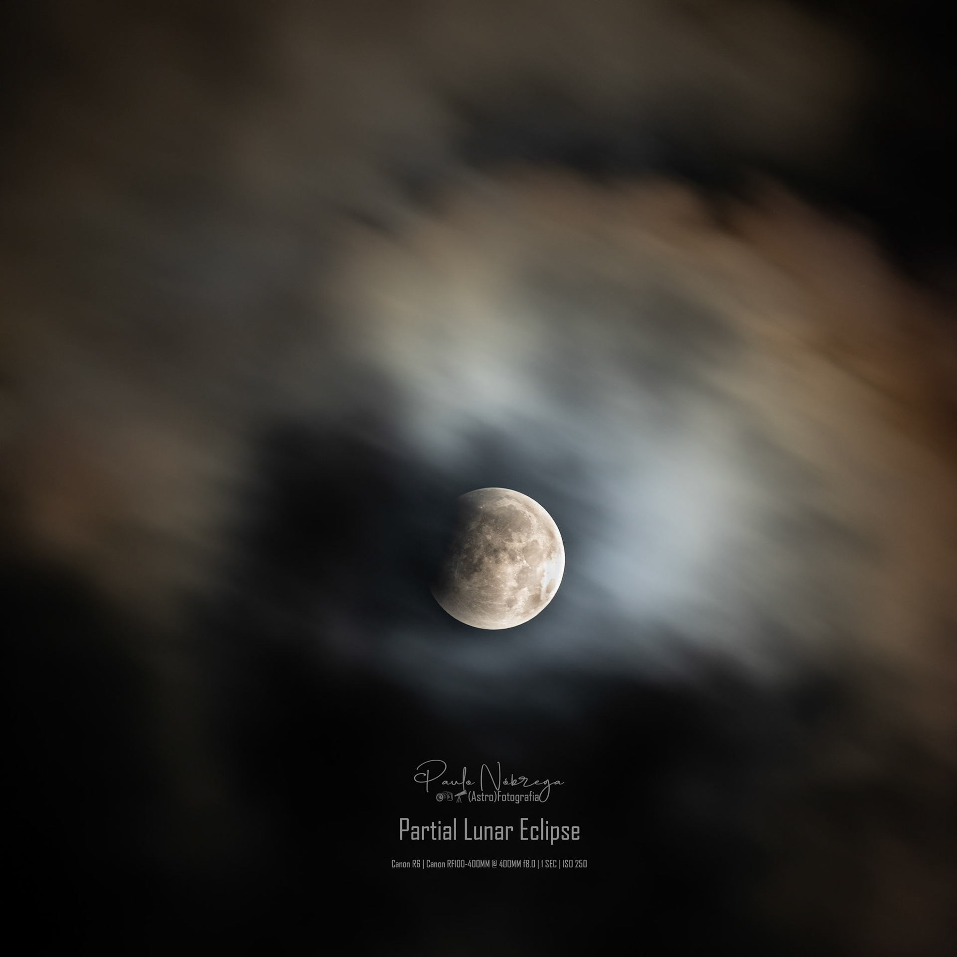 Atmospheric transit. A single exposure of the Partial Lunar Eclipse captured through passing clouds, balancing the bright sunlit maria with the soft glow diffused across the night sky.
