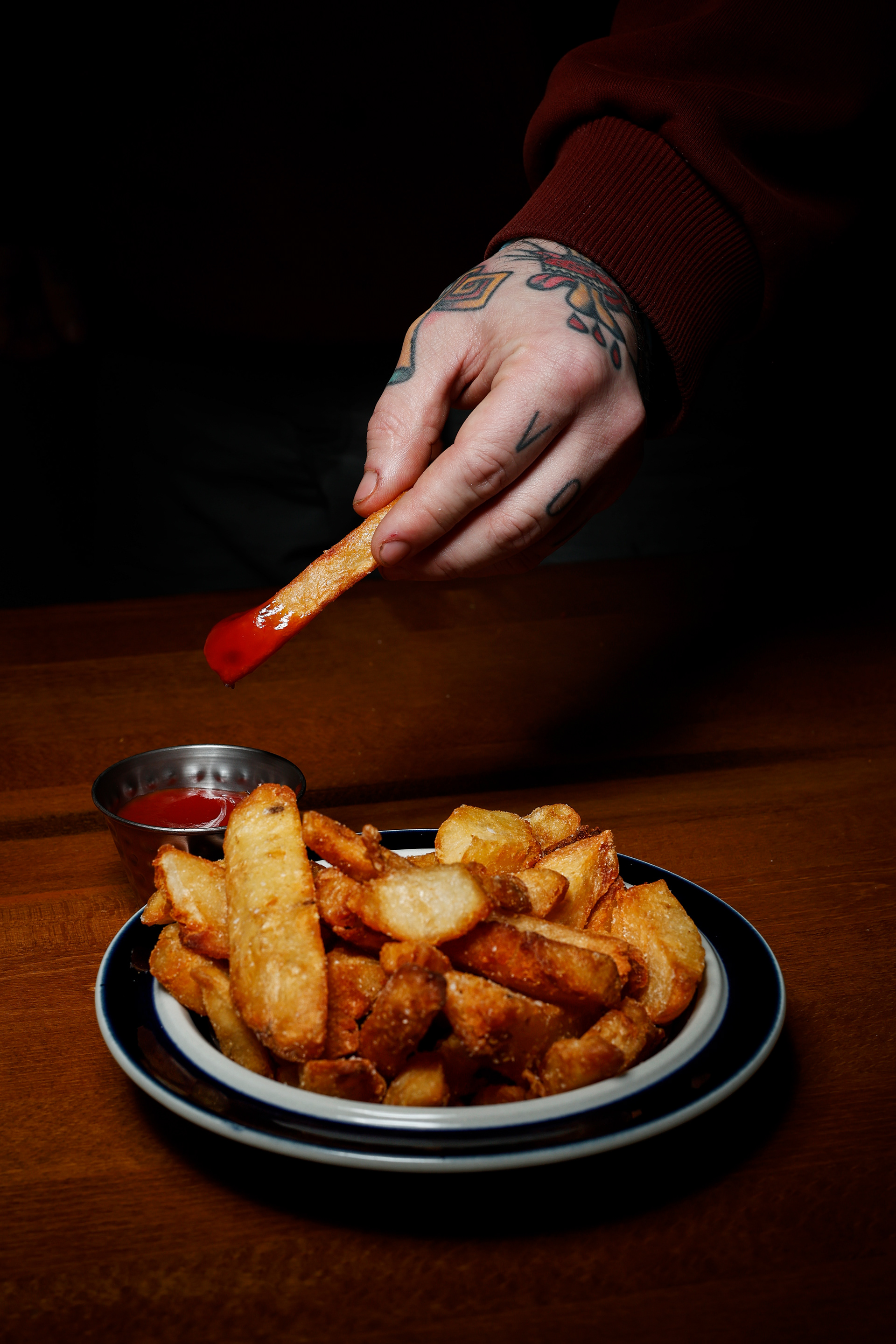 A french fry is dipped in ketchup and held on Wednesday, March 11, 2026 at Zeebo's in Long Beach, N.Y.