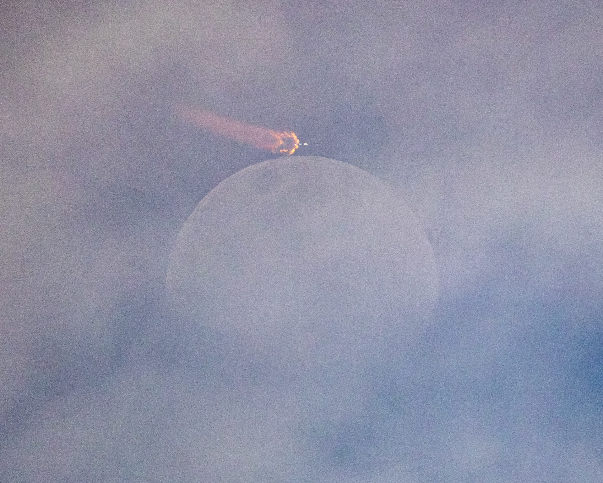 SpaceX Falcon 9 rocket carrying a batch of Starlink satellites to orbit Thursday night, caught through clouds as it flew over the Moon.