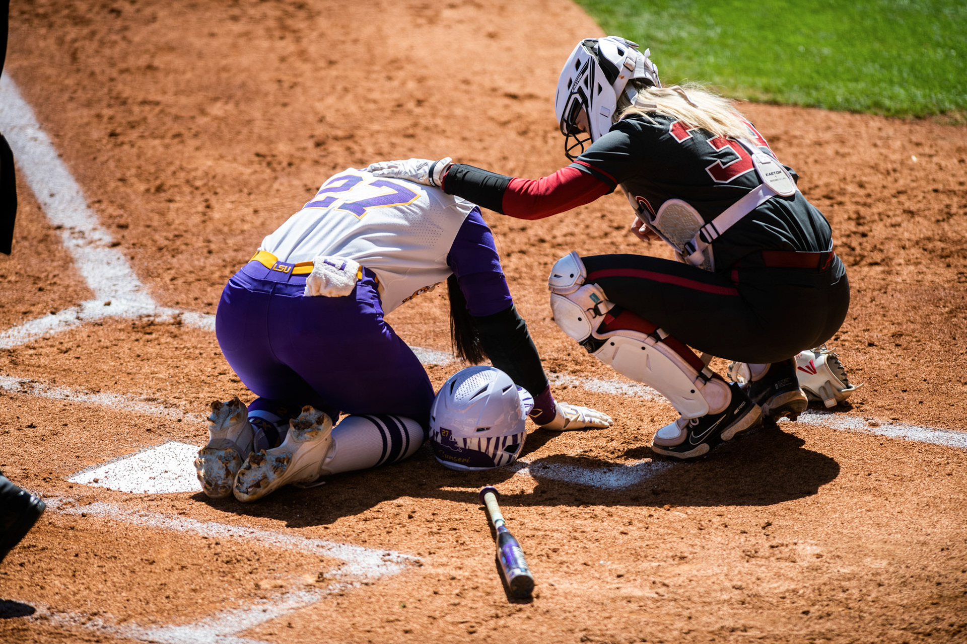 LSU softball 5th-year senior pitcher/utility Shelbi Sunseri (27) kneels in pain while Alabama softball senior catcher Ally Shipman makes sure she is okay Saturday, March 12, 2022 during LSU's 13-6 win against Alabama at Tiger Park in Baton Rouge, La.