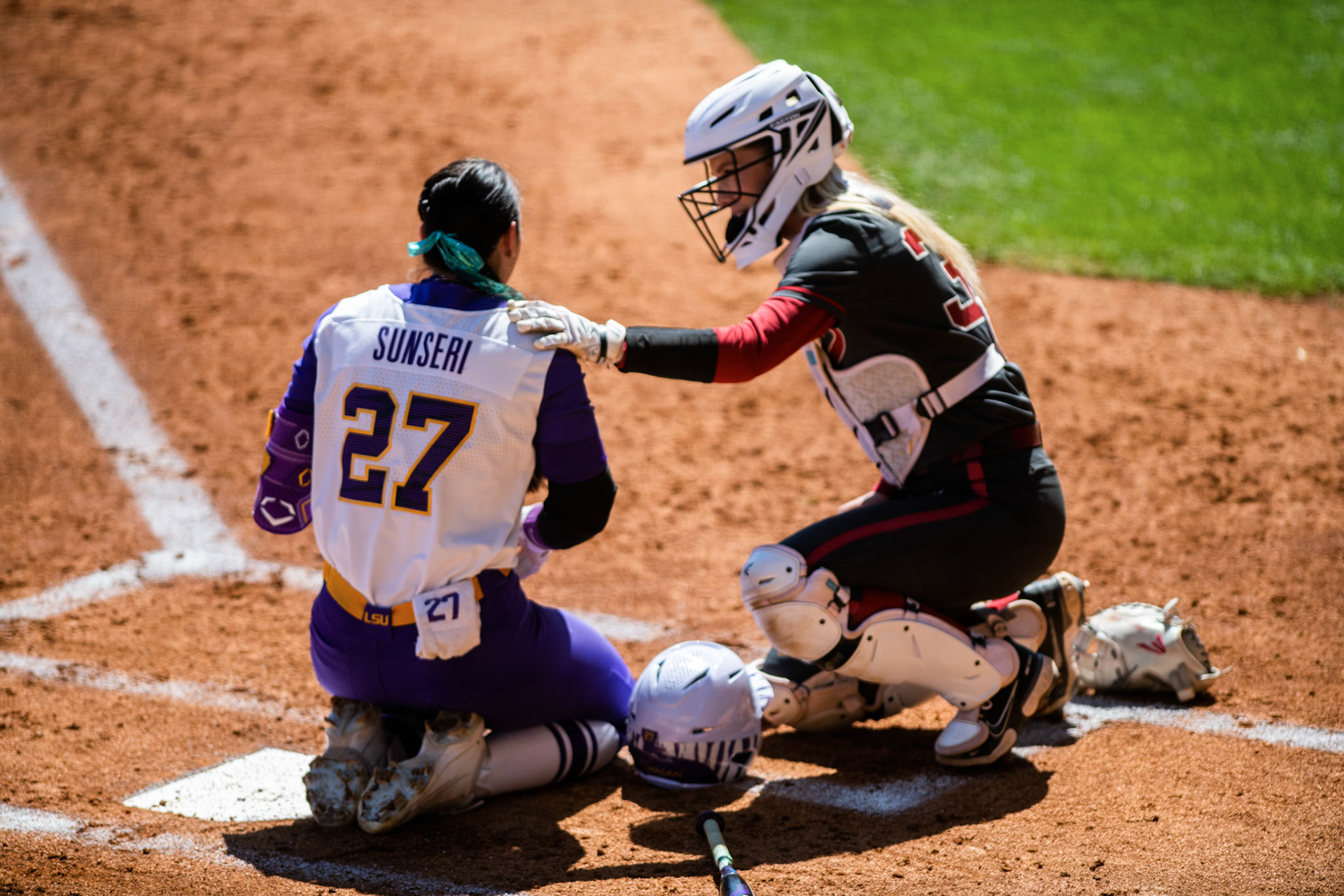 LSU softball 5th-year senior pitcher/utility Shelbi Sunseri (27) kneels in pain while Alabama softball senior catcher Ally Shipman makes sure she is okay Saturday, March 12, 2022 during LSU's 13-6 win against Alabama at Tiger Park in Baton Rouge, La.