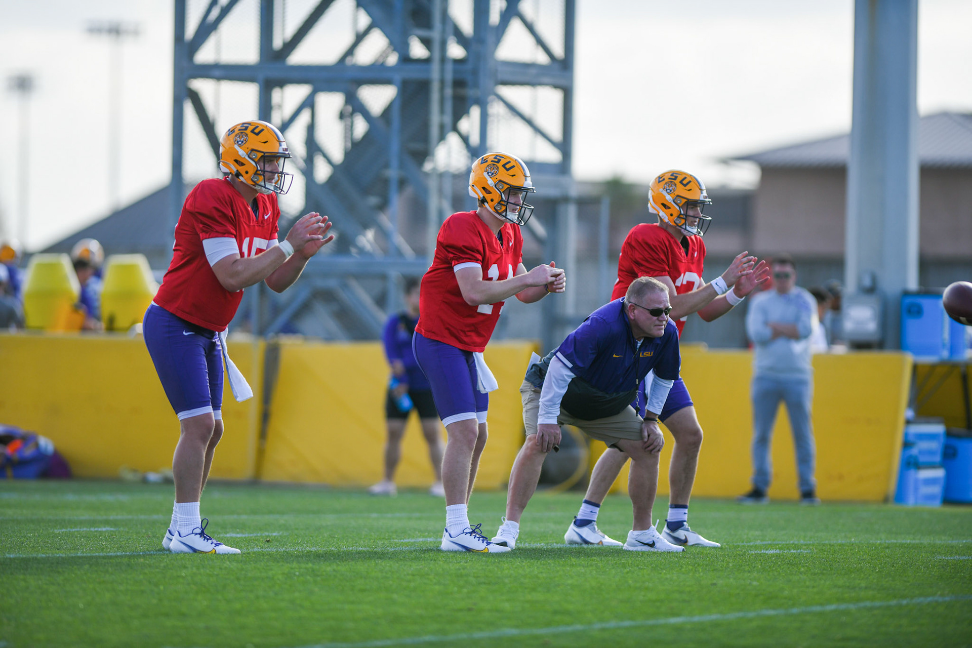 LSU football quarterbacks Garrett Nussmeier (13), Walker Howard (14), and Myles Brennan (15) prepare for the ball while head coach Brian Kelly stands inbetween them Tuesday, March 29, 2022 during LSU's spring practice in Baton Rouge, La.