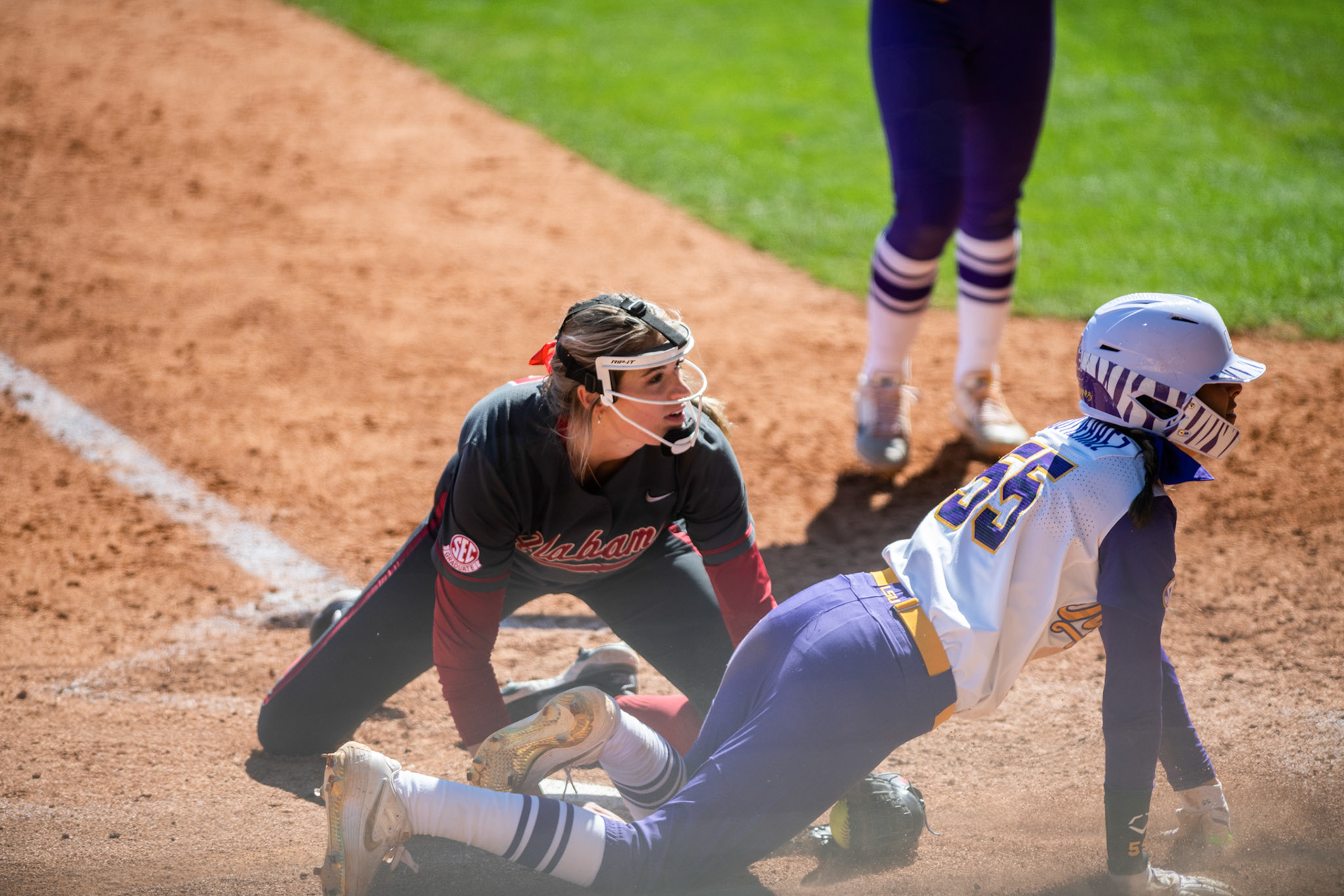 LSU softball redshirt sophomore Raeleen Gutierrez (55) and Alabama softball senior pitcher Montana Fouts (14) look at the umpire to see if Raeleen is safe or out Saturday, March 12, 2022 during LSU's 13-6 win against Alabama at Tiger Park in Baton Rouge, La.