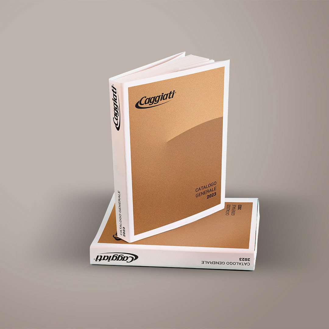 Mockup del catalogo generale Caggiati 2023 con due copie, una aperta e una verticale sovrapposta, per presentazione collezioni arte funeraria.