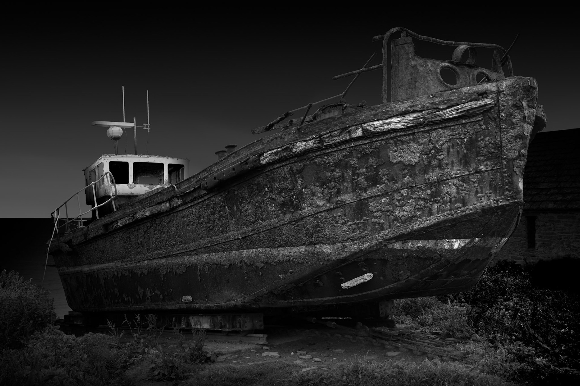 Boats were once fundamental to life on Stroma. The Pentland Firth provided both opportunity and danger, connecting the islanders with fishing and the mainland while simultaneously creating one of the greatest obstacles to permanent settlement. This abandoned vessel now rests out of the water, its working life apparently finished but its form still strikingly intact. I was interested in photographing it less as maritime nostalgia than as another piece of redundant human infrastructure. By isolating the hull against the darker surroundings, its scars, textures and substantial physical presence become prominent. Like the crofts and agricultural equipment elsewhere on the island, it survives as evidence of work: an object made and maintained for a practical purpose that has outlasted the circumstances which once made it necessary.Stroma is an ongoing photographic project which I am currently developing.