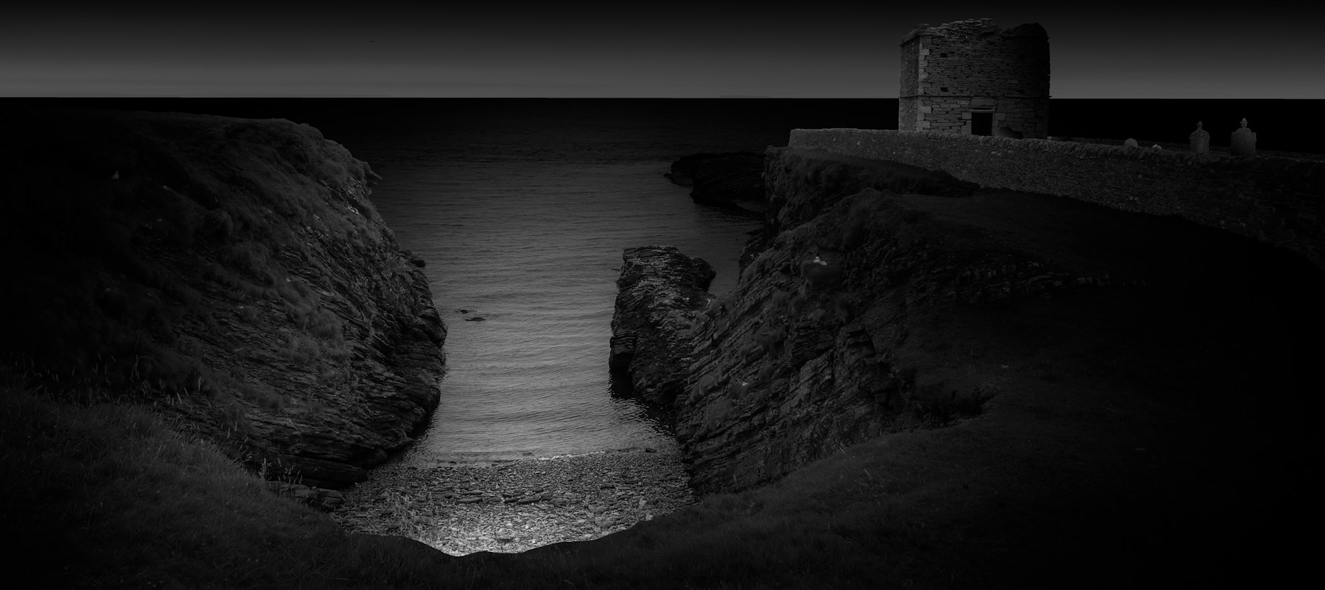 Fullie Geo is a narrow coastal inlet cut into Stroma's rocky shoreline, a reminder that the human history recorded throughout this project exists within a landscape shaped by considerably older and more powerful forces. The sea has always defined life on Stroma, providing fishing and communication while the formidable tidal waters of the Pentland Firth separated the island from mainland Caithness. After concentrating much of the project on buildings, objects and interiors, I wanted photographs that allowed the physical island itself to reassert its presence. Here, the dark rock forms a natural passage towards the water and the distant horizon. Yet the human story is never far away. On the right stands the Kennedy Mausoleum within Stroma's graveyard, where the naturally preserved bodies known as the “Stroma Mummies” became something of a tourist attraction during the late eighteenth century. I was drawn to this juxtaposition: the geo leads the eye outward towards the Pentland Firth, while the mausoleum anchors it firmly to the island's human past. Land, sea, life and death occupy the same small piece of Stroma.Stroma is an ongoing photographic project which I am currently developing.