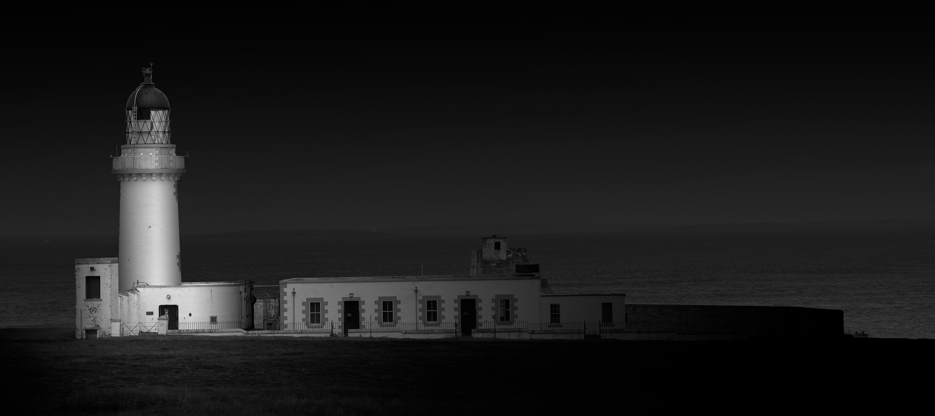 Standing at Silkie Point on Stroma's northern coast, the lighthouse is one of the island's most prominent surviving structures. Built in 1896 (by David A &amp; Charles Stevenson) to safeguard vessels navigating the notoriously difficult waters of the Pentland Firth, it represents another aspect of Stroma's long relationship with the sea. Unlike the island's abandoned crofts, the lighthouse continued to have an active human presence long after the permanent population had departed, remaining manned until its automation in the late 1990s. I have photographed it almost as a pool of illumination within the surrounding darkness, allowing the white tower and associated buildings to emerge from the landscape. Its ordered geometry contrasts with the ruined domestic structures elsewhere on Stroma and provides a reminder that the island's history did not simply end when its community left.Stroma is an ongoing photographic project which I am currently developing.